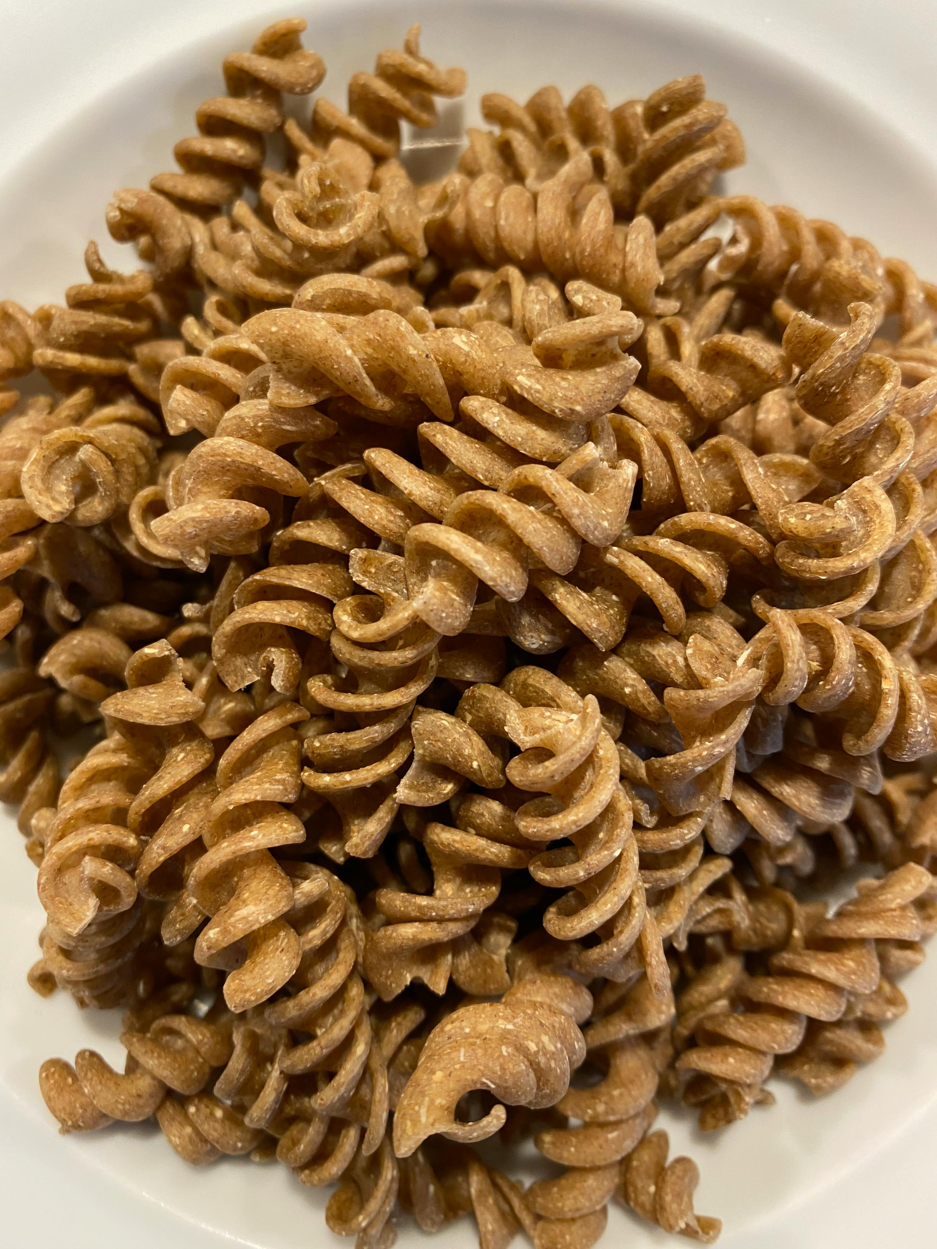 un piatto bianco pieno di fusilli di grano integrale