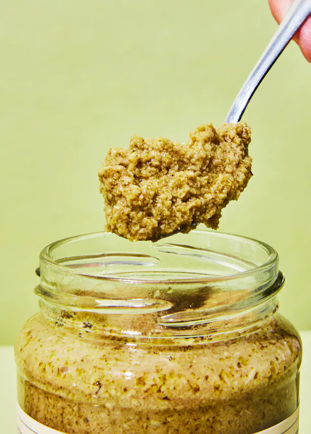 une personne tient une cuillère remplie de sauce à l' intérieur d' un bocal