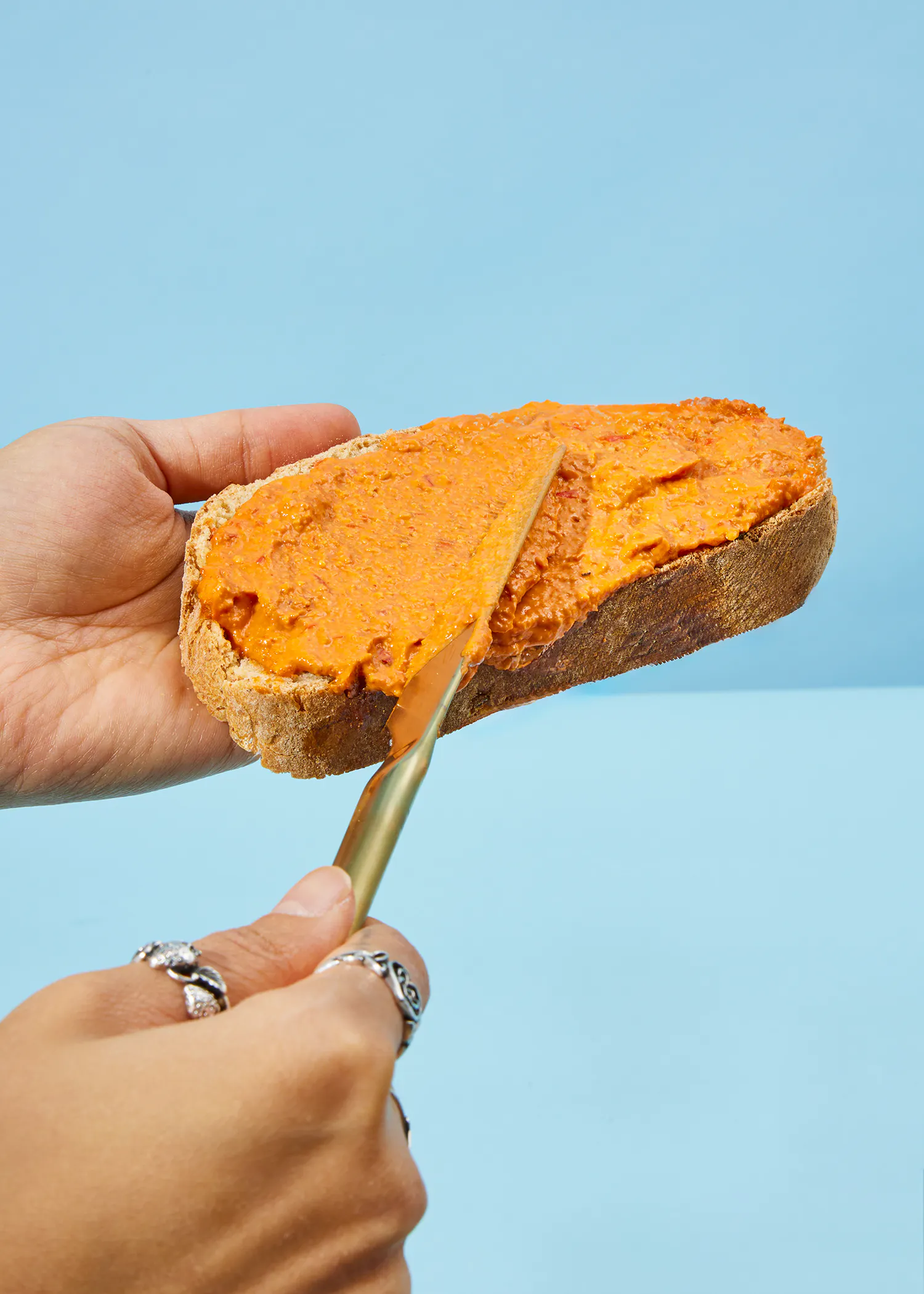 Eine Person spreads eine rote Soße auf ein Stück Brot