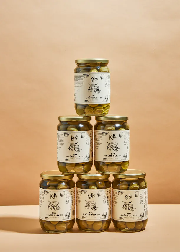 several jars of green olives are stacked on top of each other