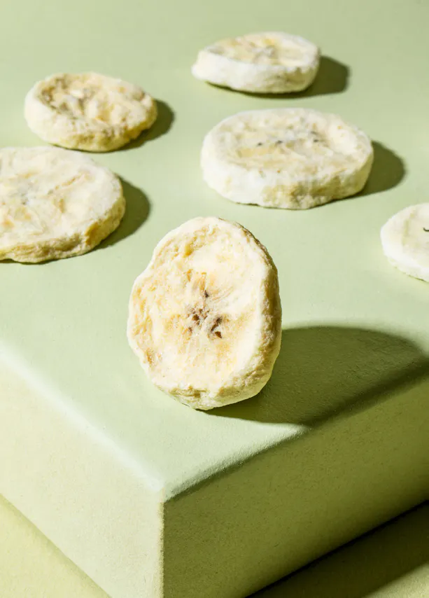 une banane séchée est assise sur une surface verte