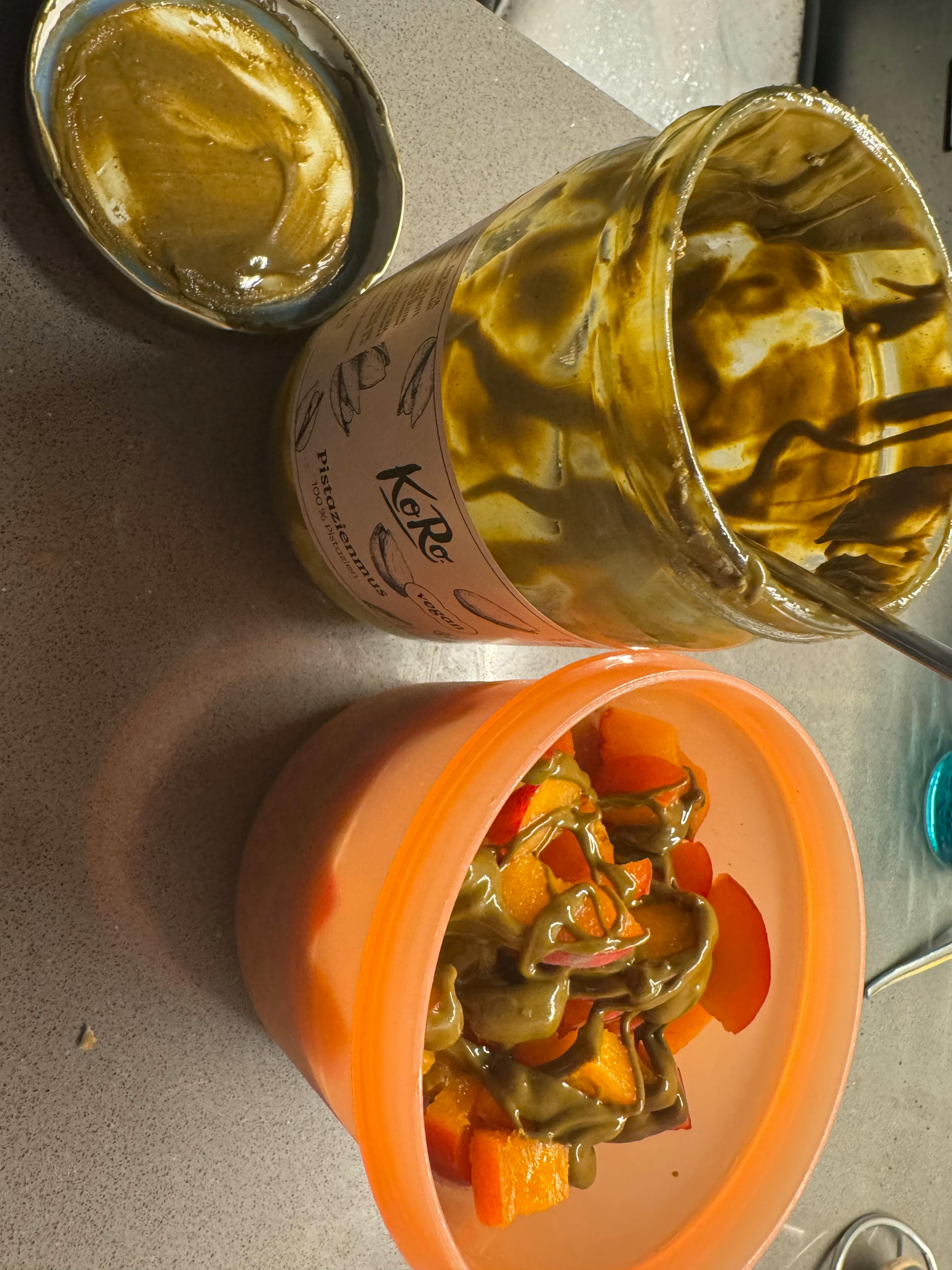 un bocal de koré pistachio butter est assis à côté d' un bol de fruits