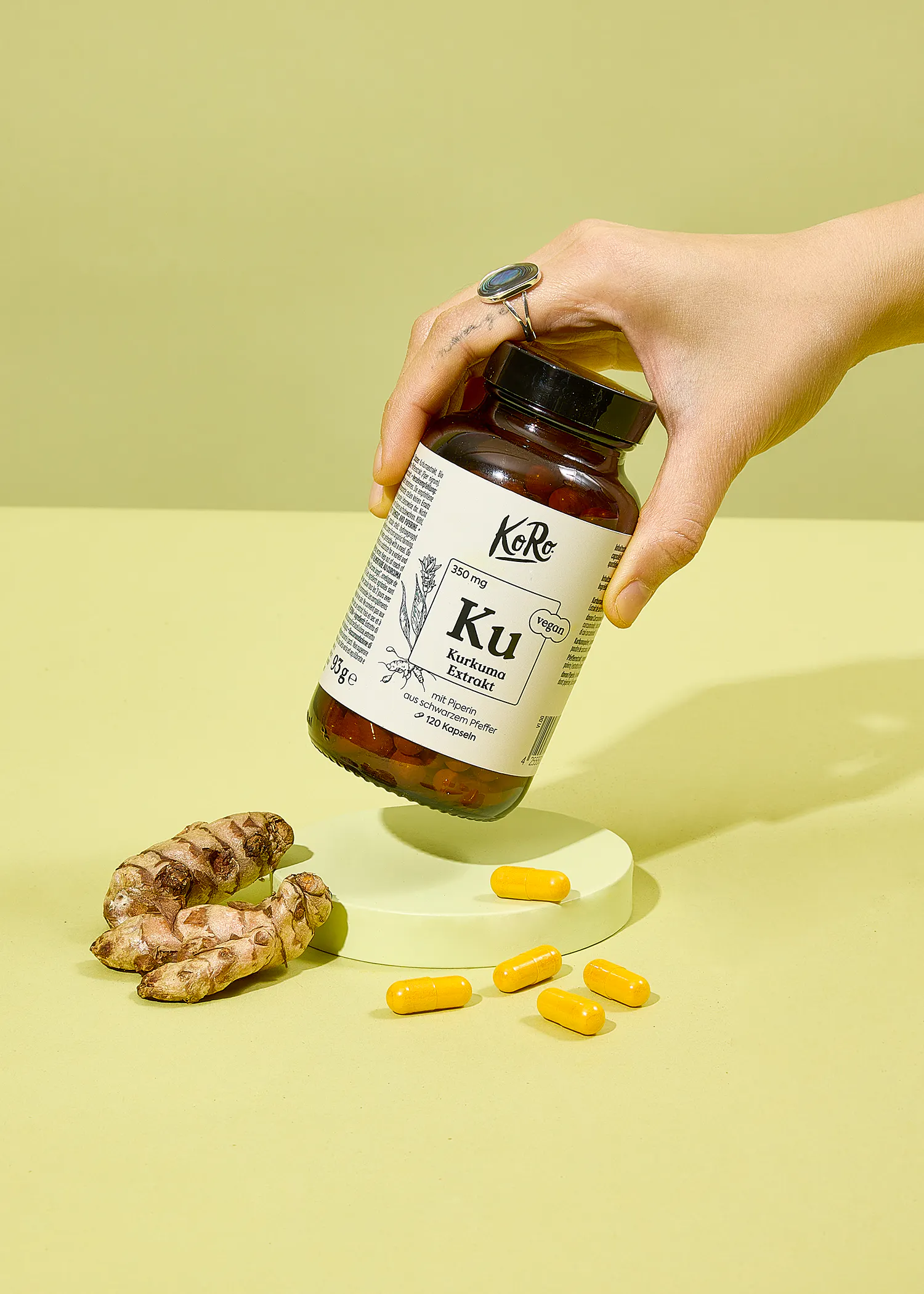 une personne tient une bouteille de kurkuma capsules