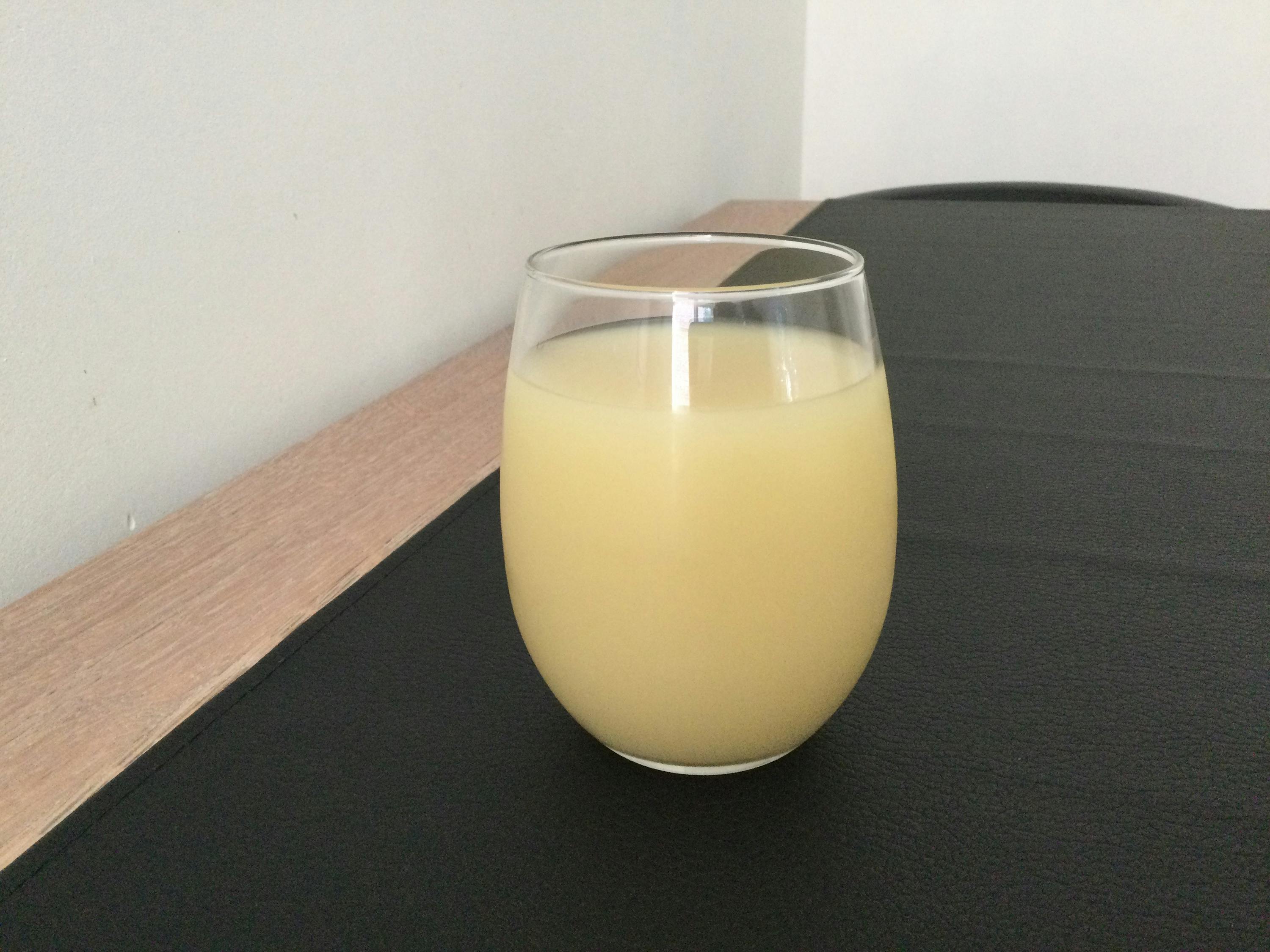 ein Glas gelber Flüssigkeit sitzt auf einem schwarzen Tisch