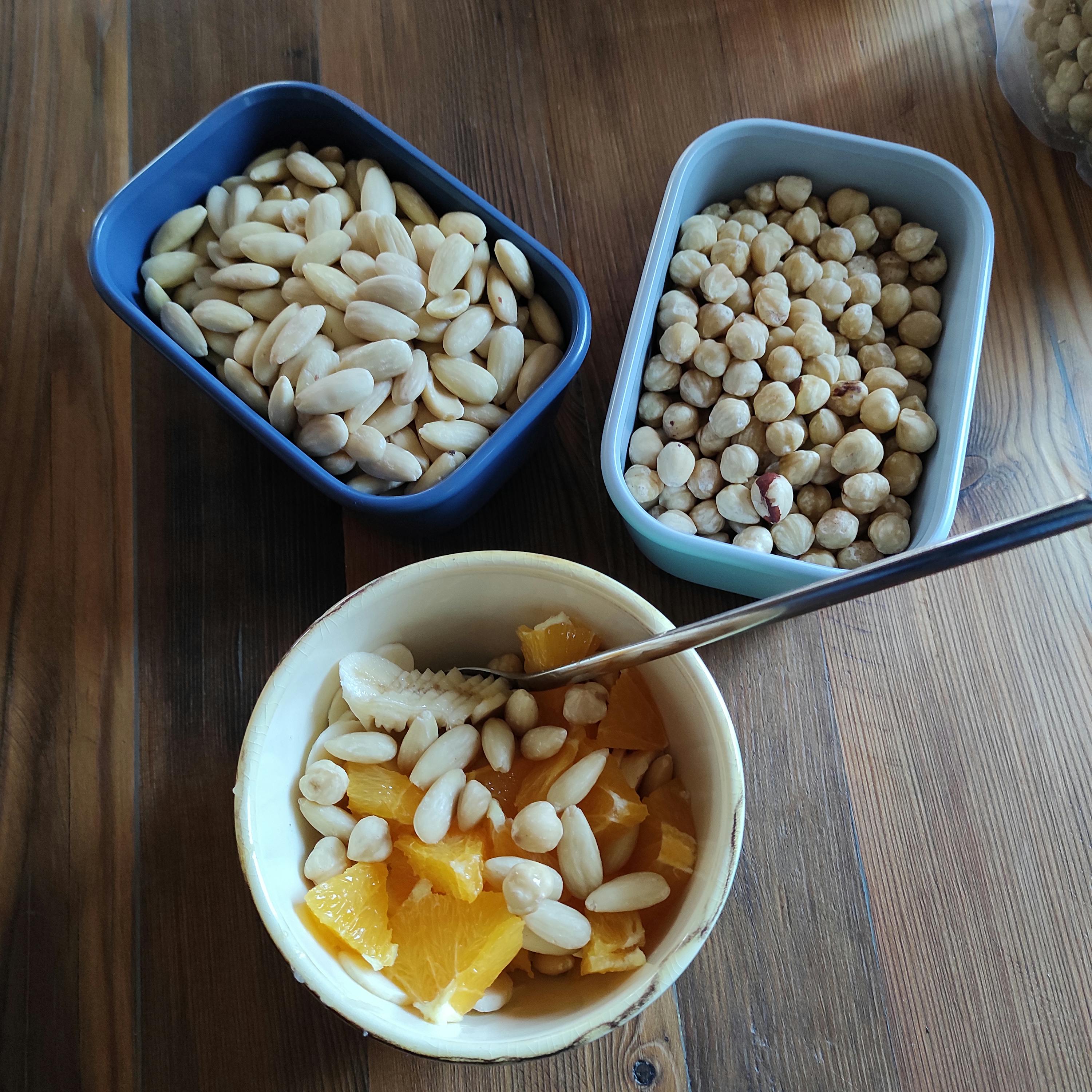 trois bols remplis de noix et de fruits sur une table en bois