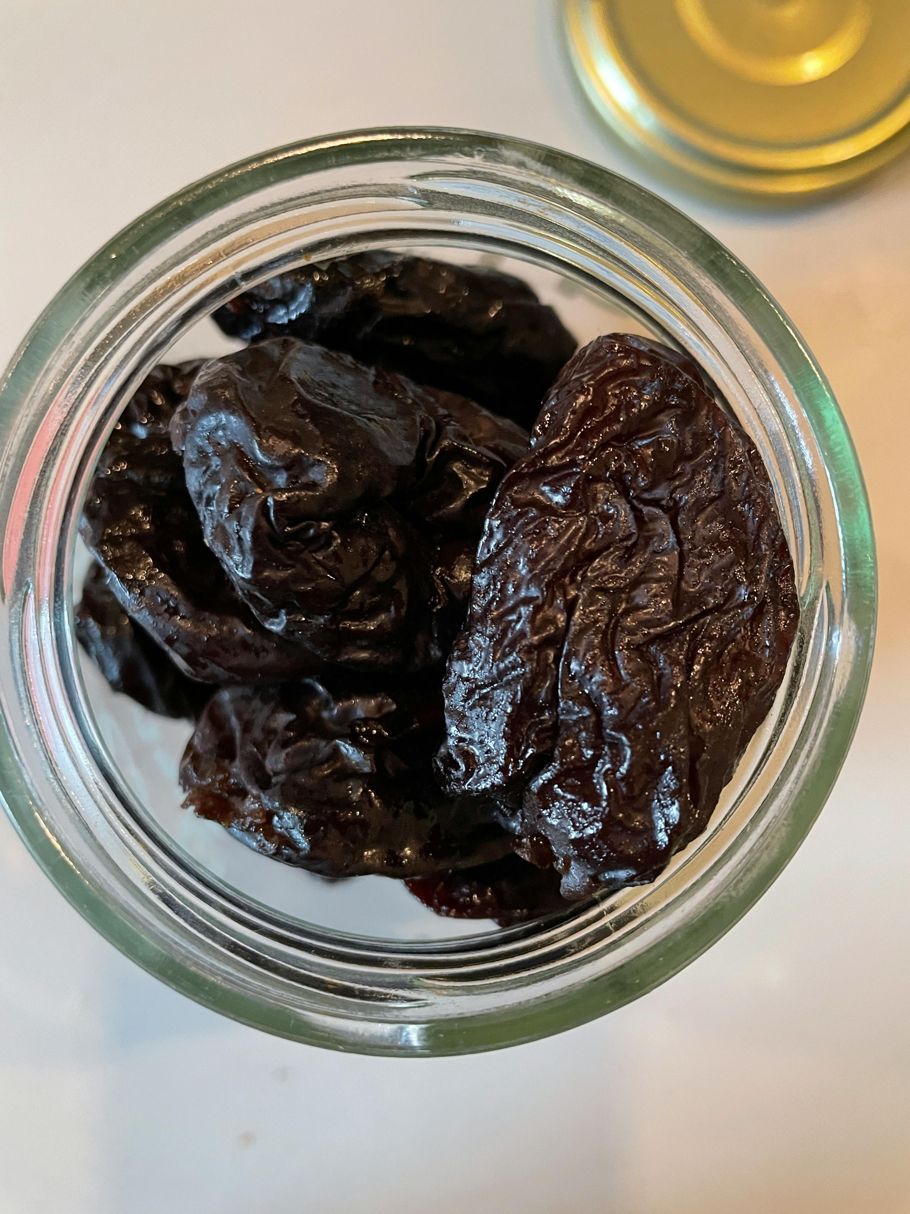 un gros plan d' un bocal rempli de prunes séchées
