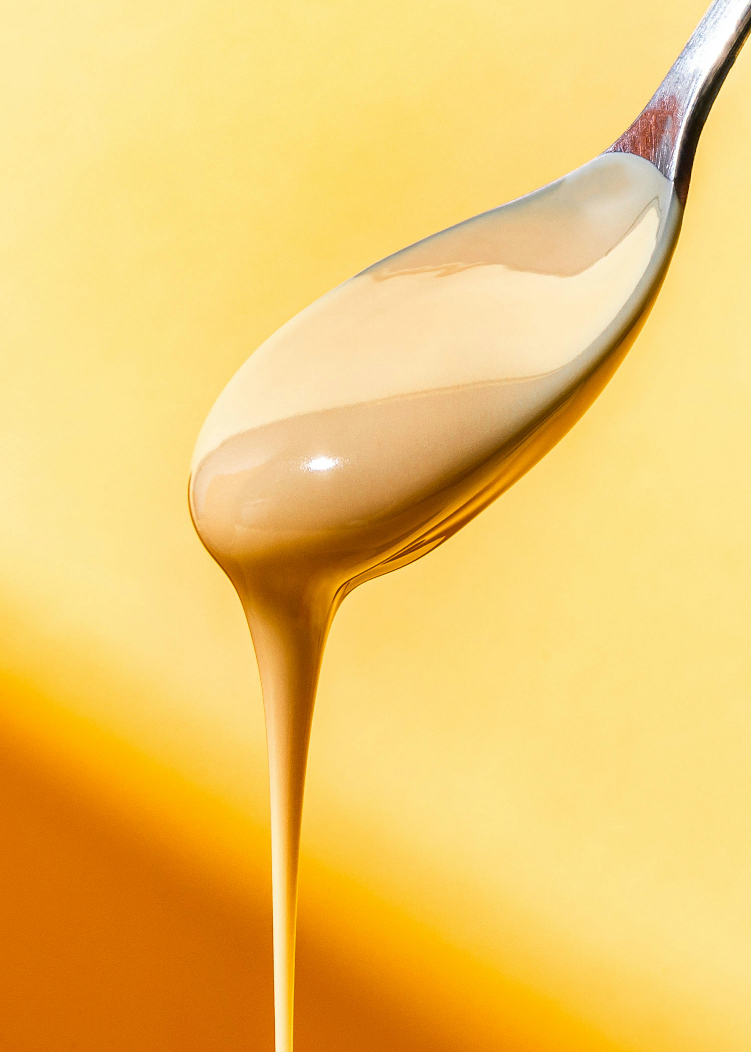 a wooden spoon with a yellow liquid pouring out of it