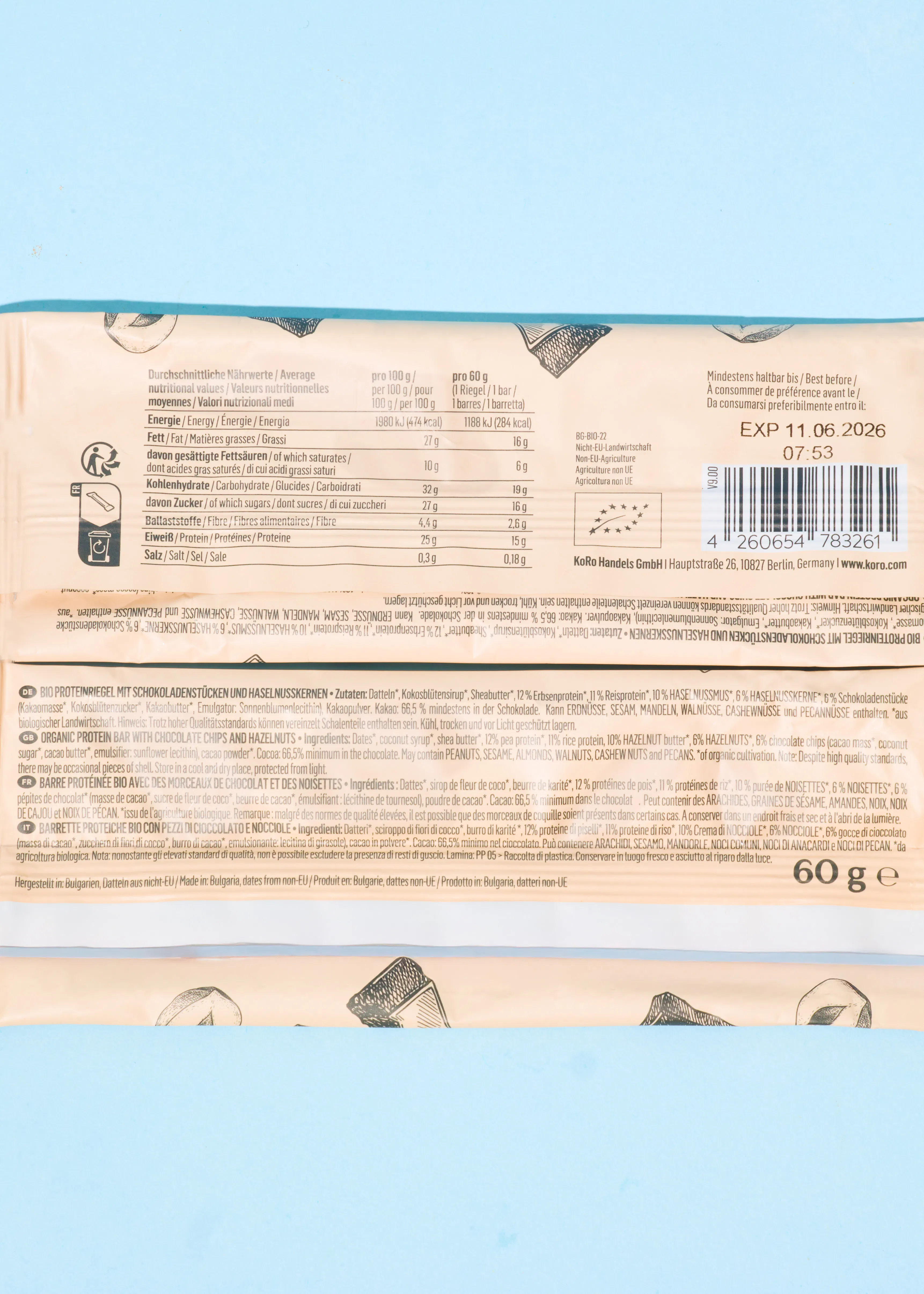 une étiquette de barre protéinée bio koro de 60g au chocolat et noisettes, affichant les informations nutritionnelles, la liste des ingrédients en plusieurs langues, un code-barres et la date de péremption au 11.06.2026.