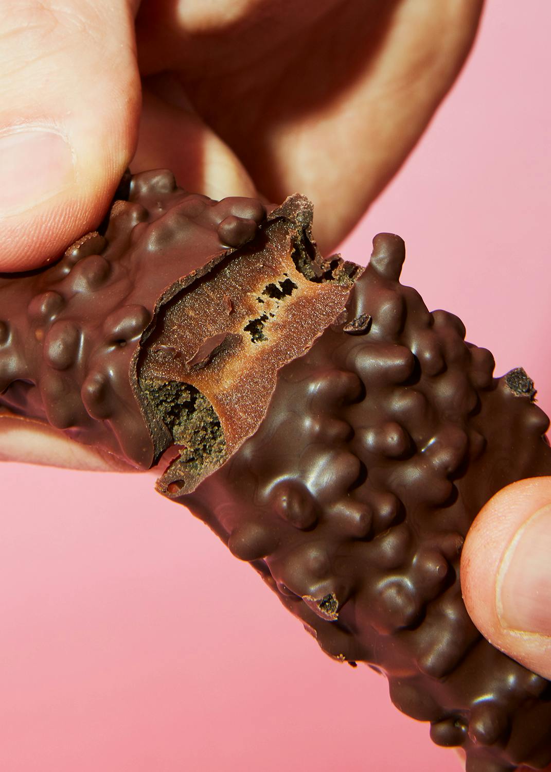 a person holding a chocolate bar with a bite taken out of it