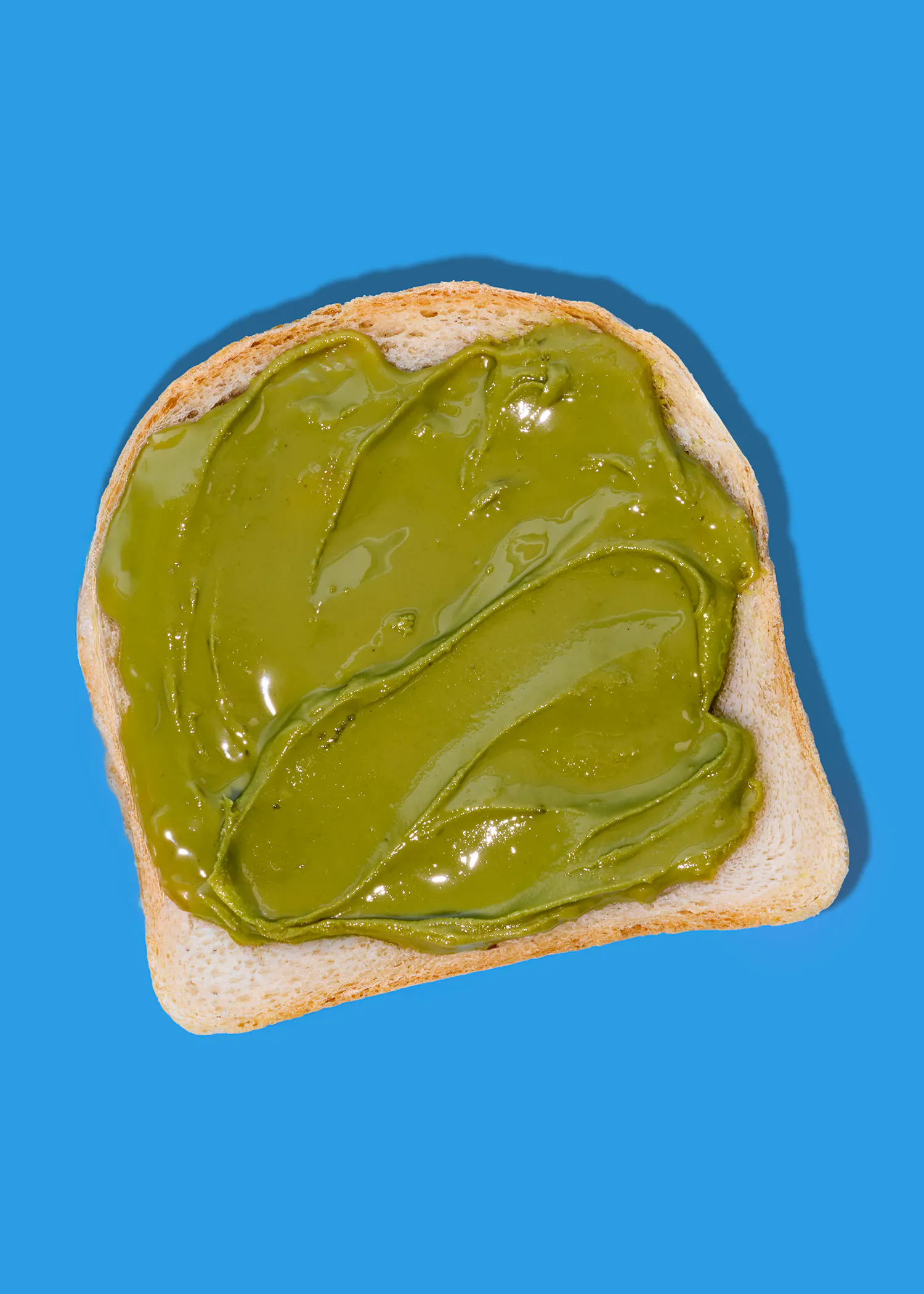 ein toastbrot mit grünem aufstrich auf blauem hintergrund.