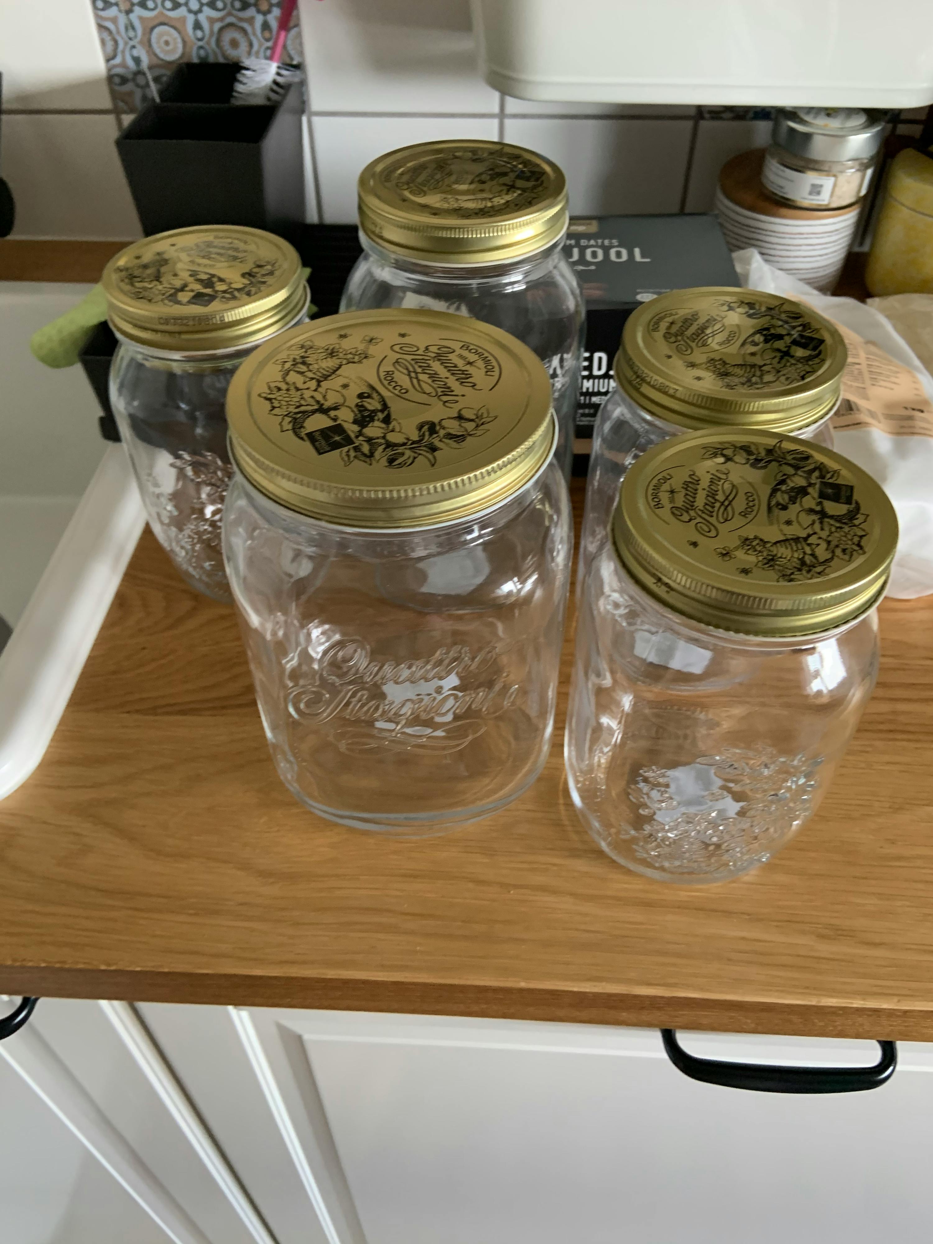 eine Reihe von Gläsern mit goldenen Deckeln auf einem Holztisch