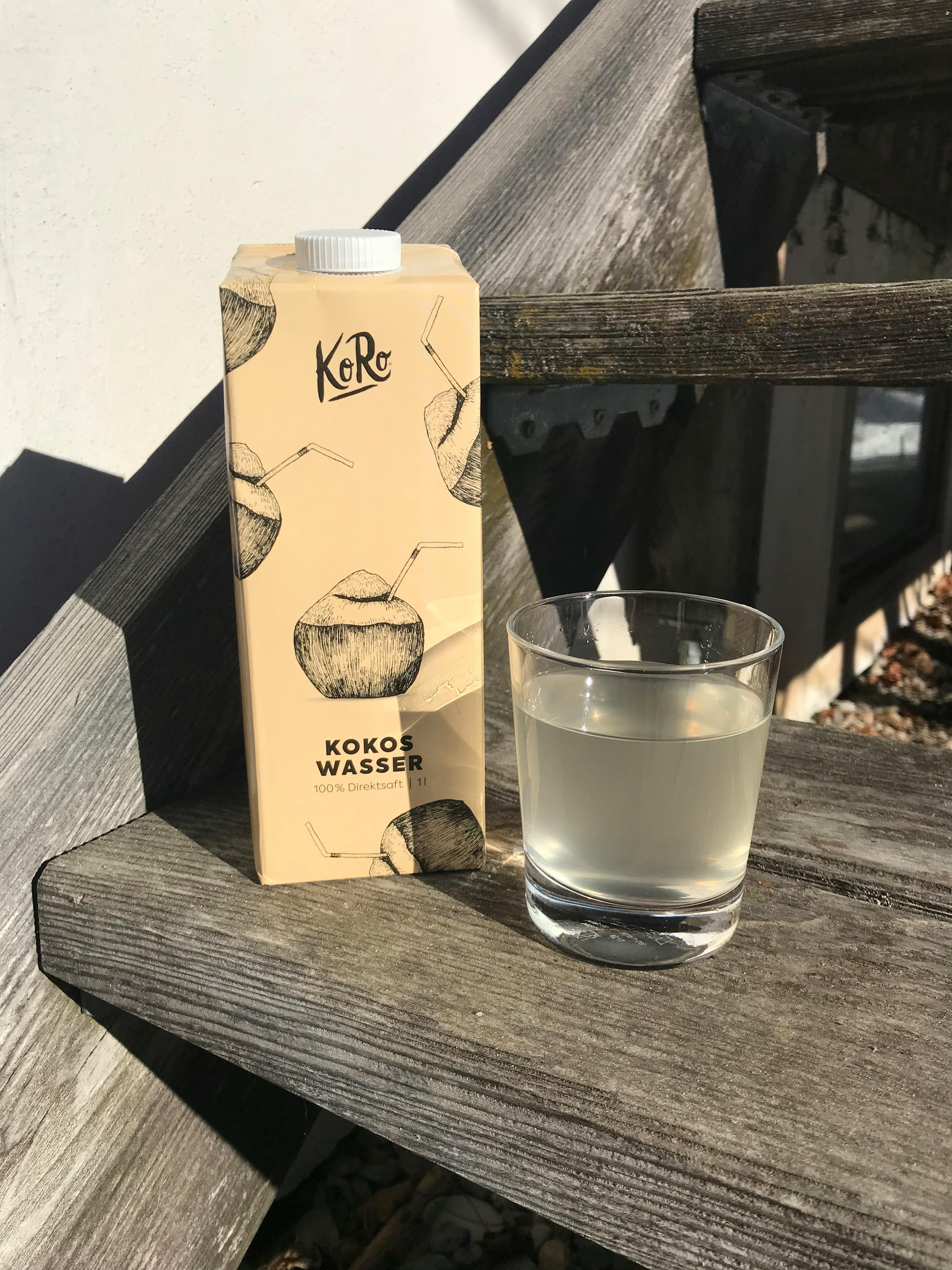 a carton of coconut water next to a glass