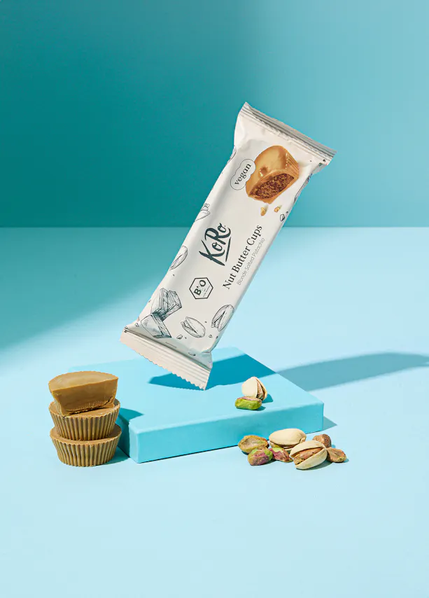 une barre de beurre de noix avec des pistaches sur une table bleue