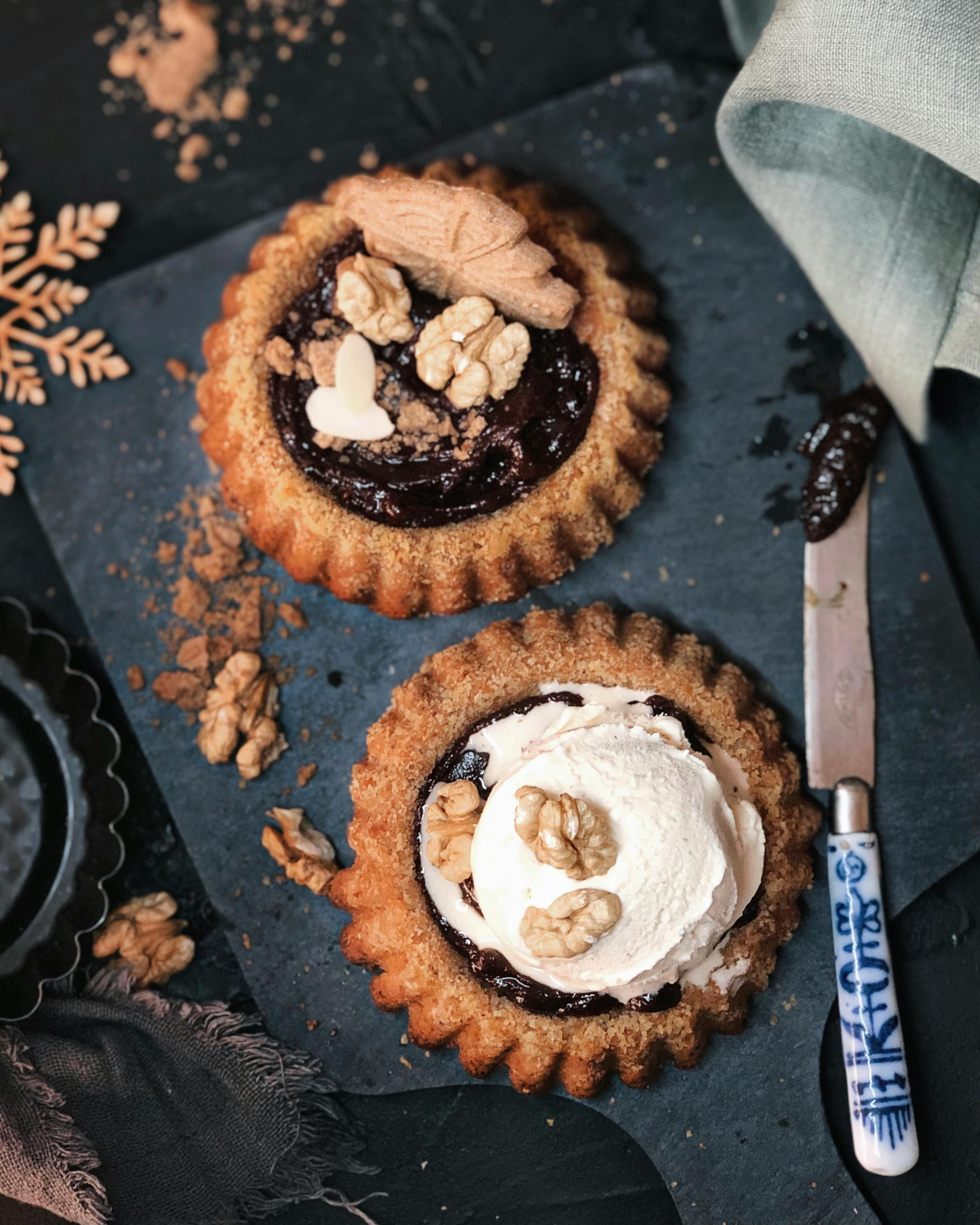 two cookies with whipped cream and walnuts on top on a table