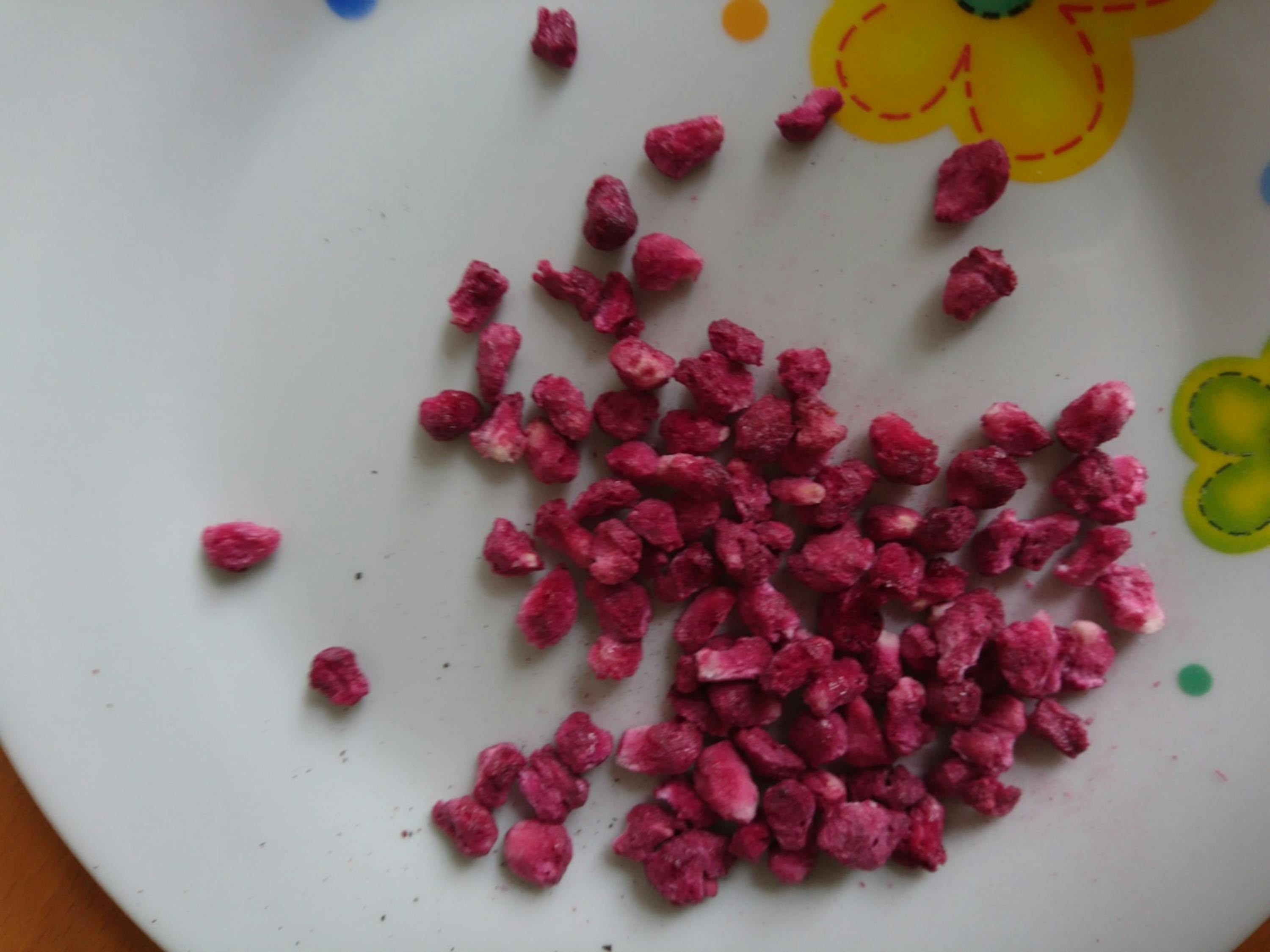 a white plate with a yellow flower on it has a bunch of pink pieces on it