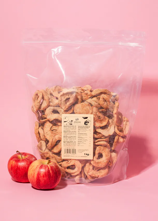 a bag of dried apple slices is on a pink surface