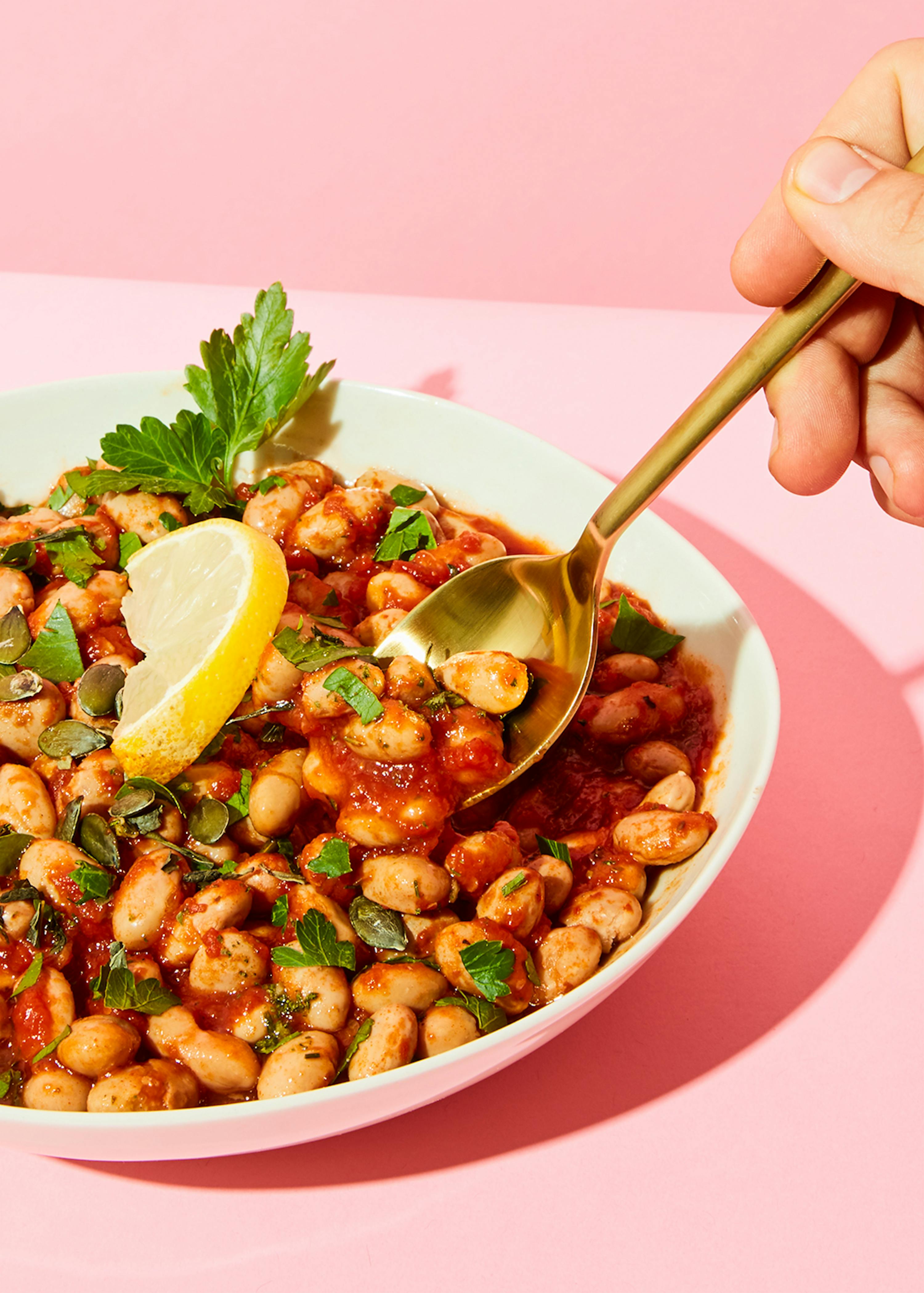 eine Person schöpft eine Schüssel Bohnensuppe mit einem Löffel aus