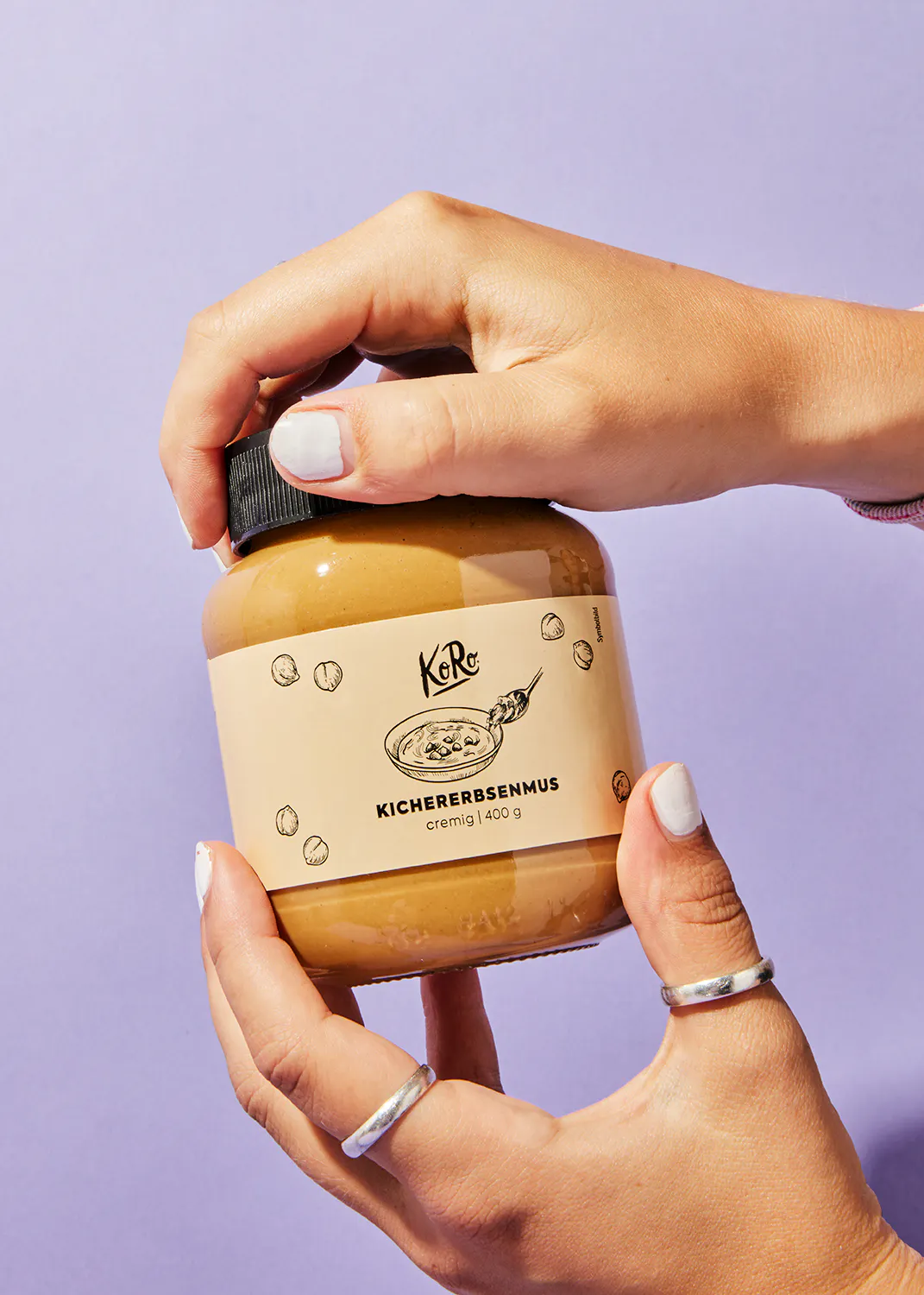 a person holding a jar of kichererbsenmus