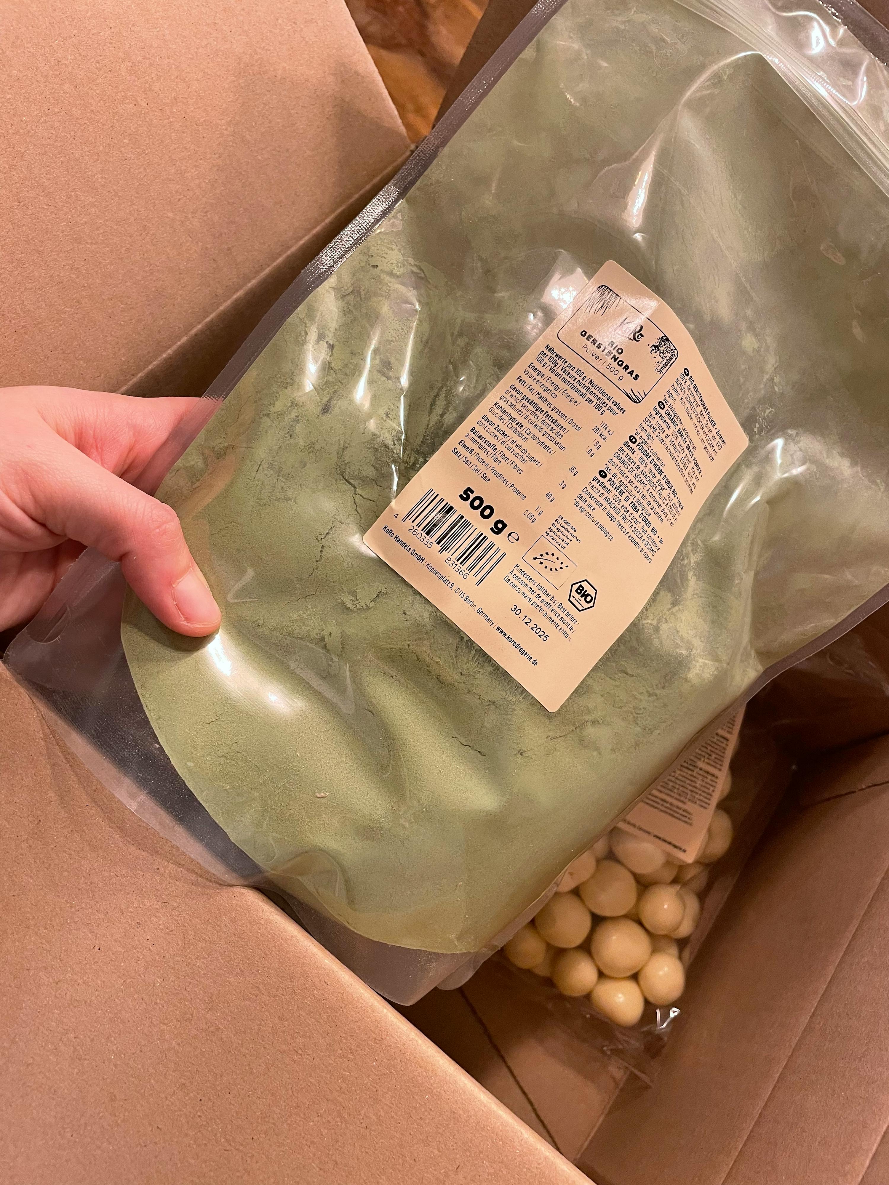 a person is holding a bag of green powder with a label that says 500g