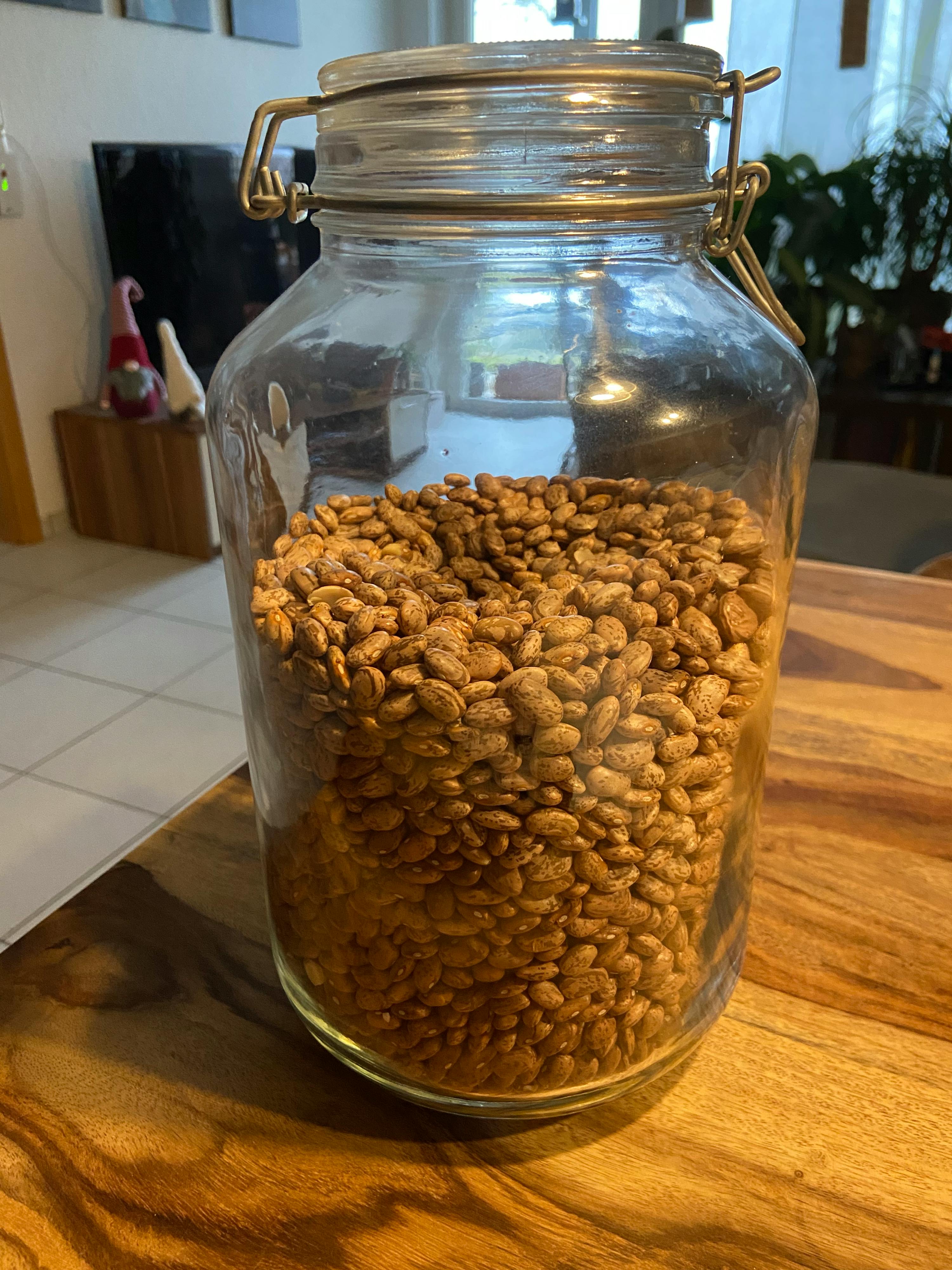 un barattolo di vetro pieno di mandorle è seduto su un tavolo di legno