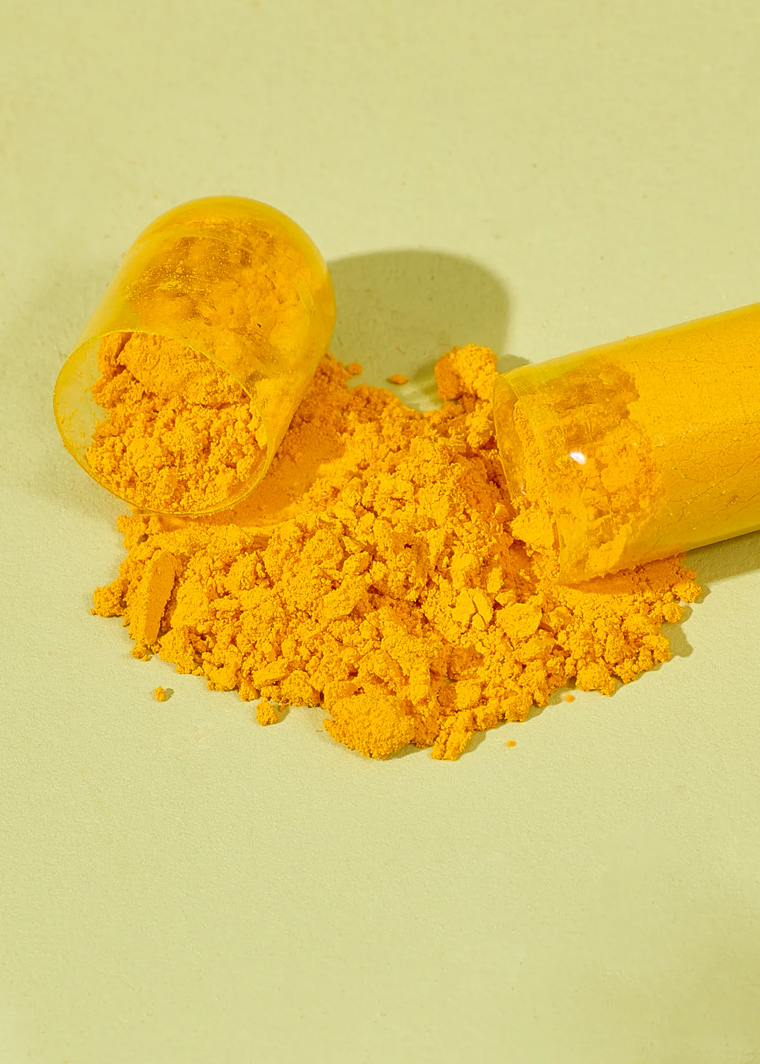 une capsule jaune est ouverte et remplie de poudre jaune