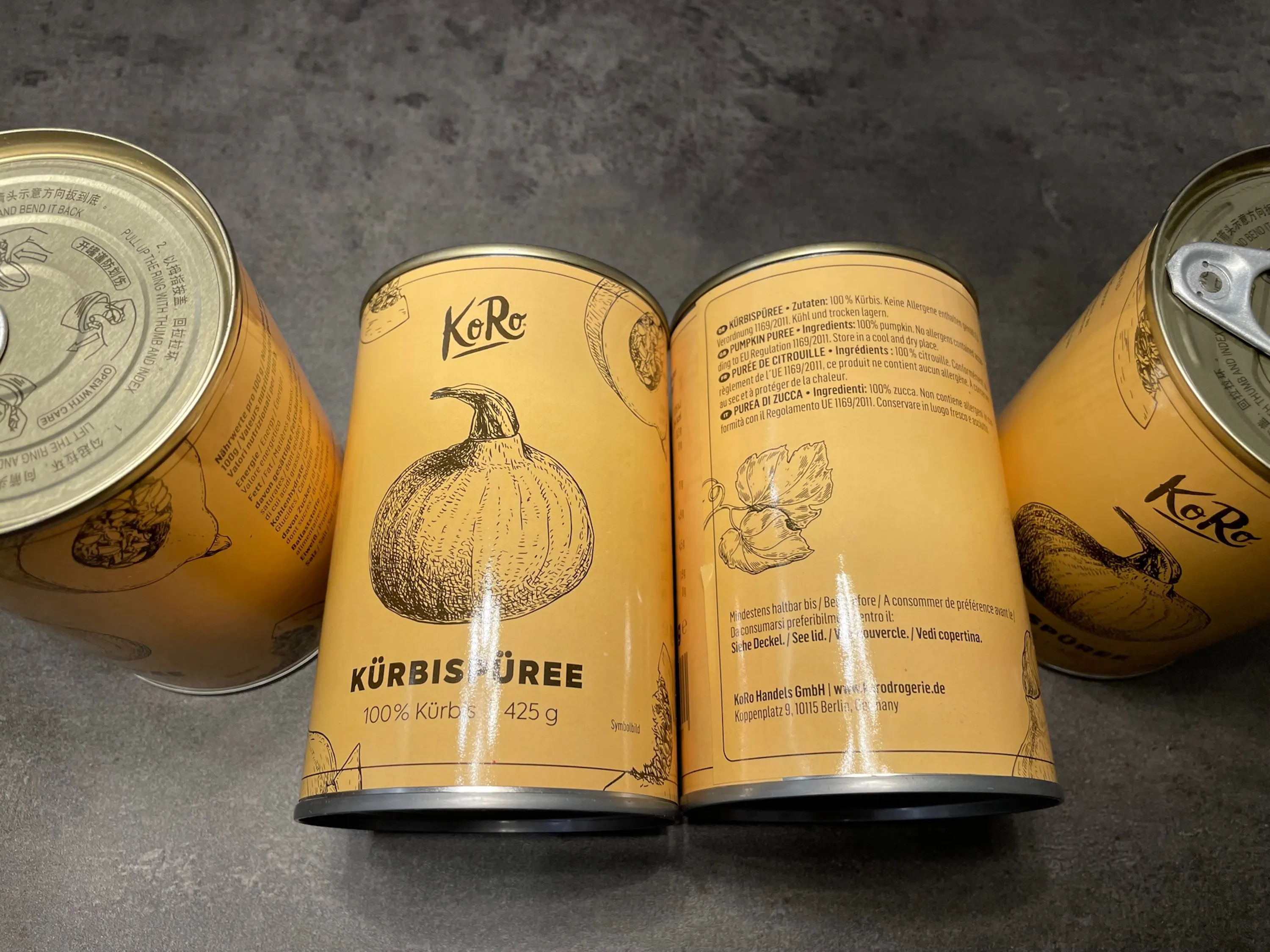 vier Dosen kürbispüree mit einem Kürbis darauf