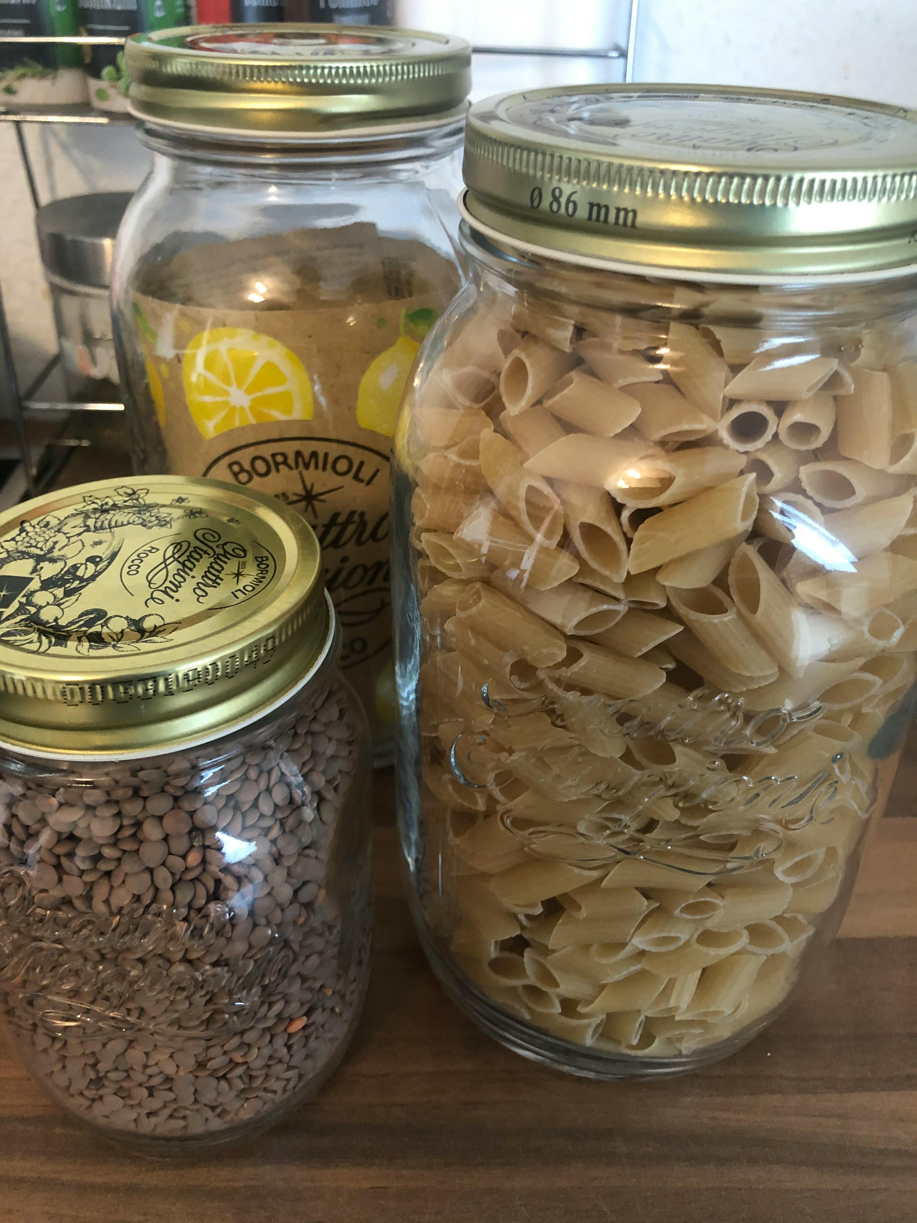 tre barattoli di vetro con pasta e lenticchie su un tavolo di legno