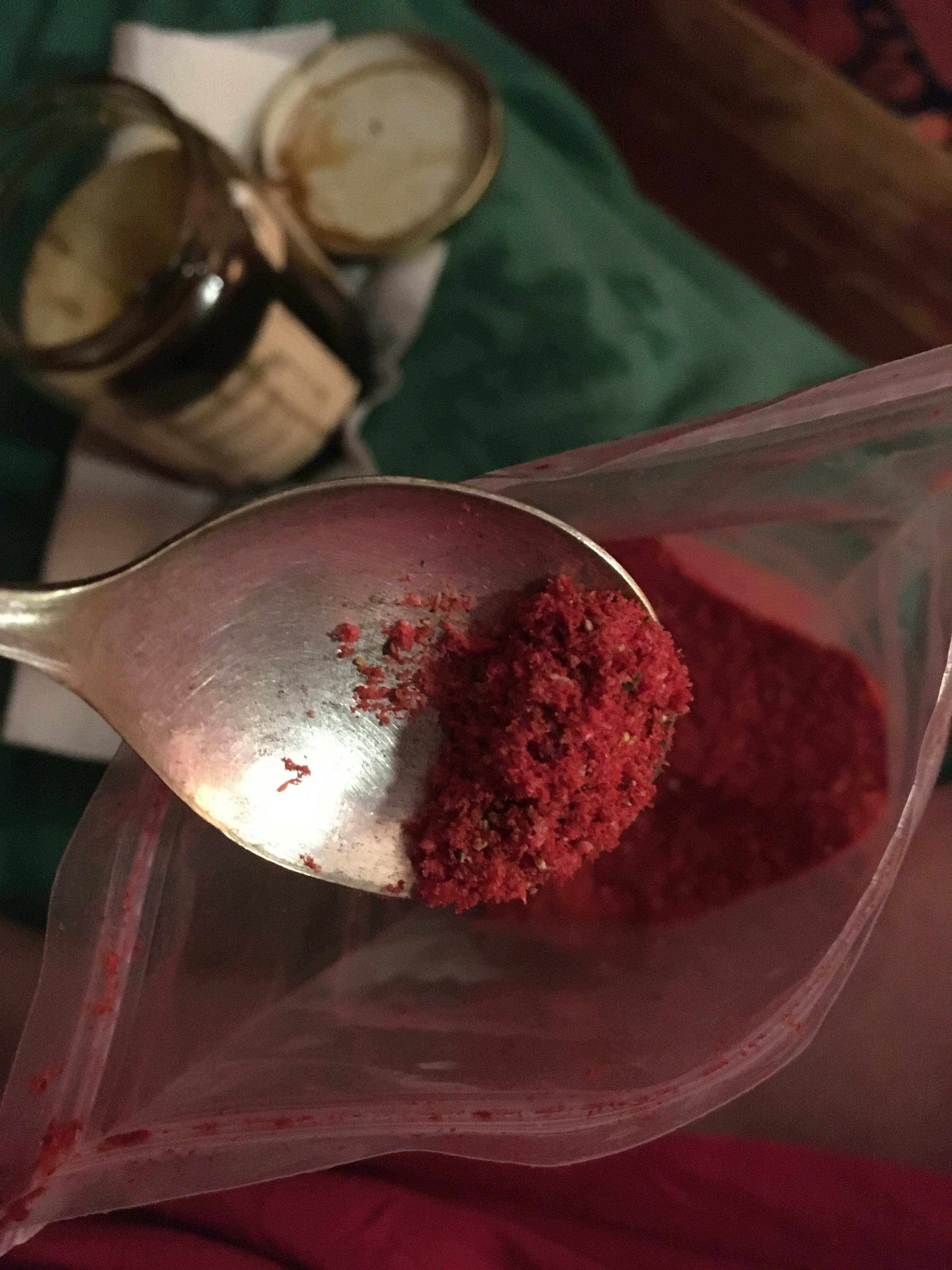 a spoon is holding a bag of red powder