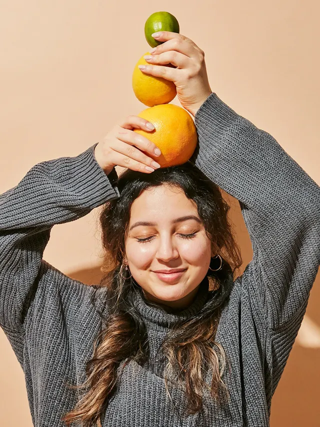 una mujer sostiene naranjas y limones sobre su cabeza
