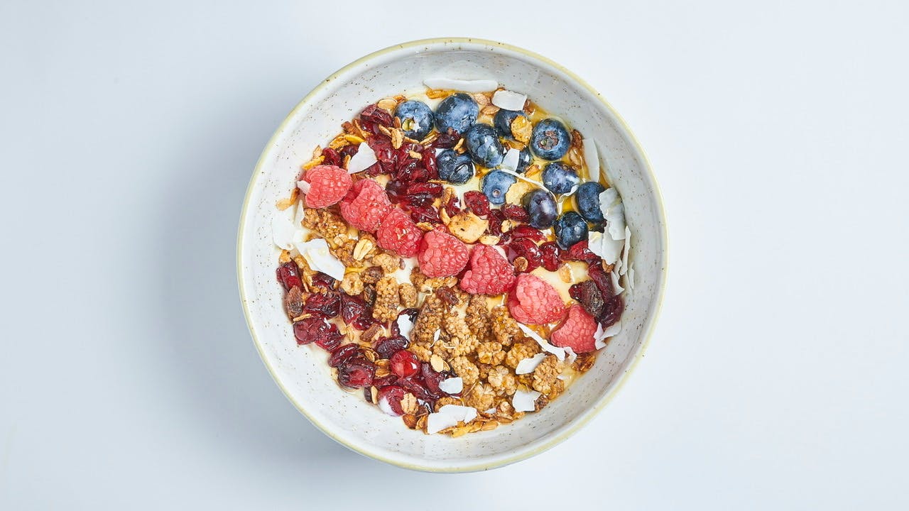 a bowl of granola with blueberries raspberries and coconut