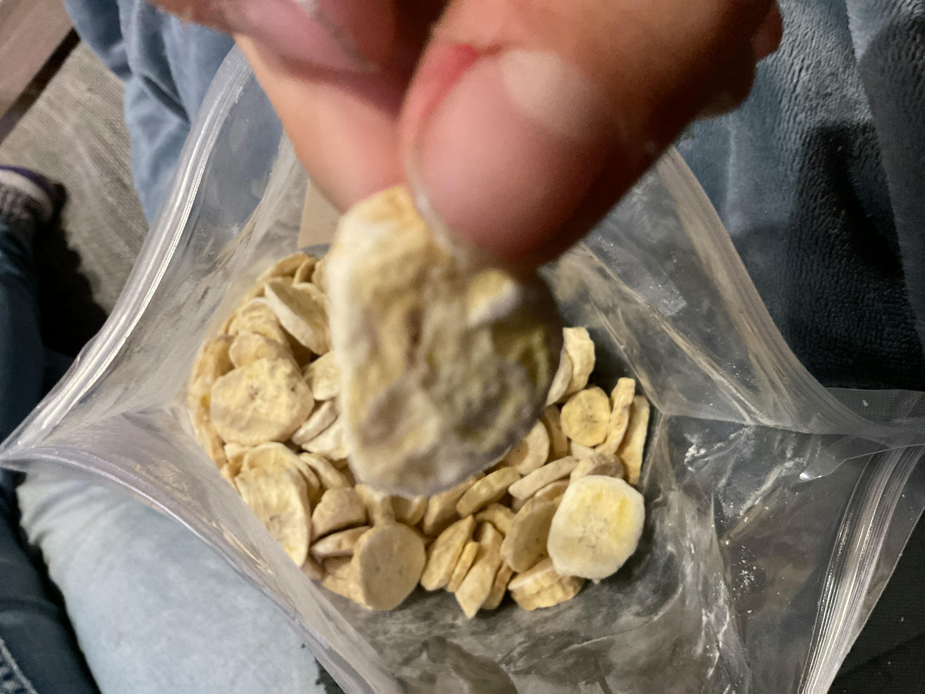 a person is holding a bag of banana chips in their hand