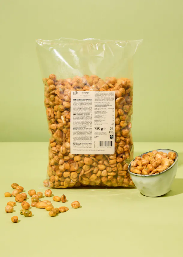 eine Tüte gesalzener Erdnüsse steht neben einer Schüssel gesalzener Erdnüsse