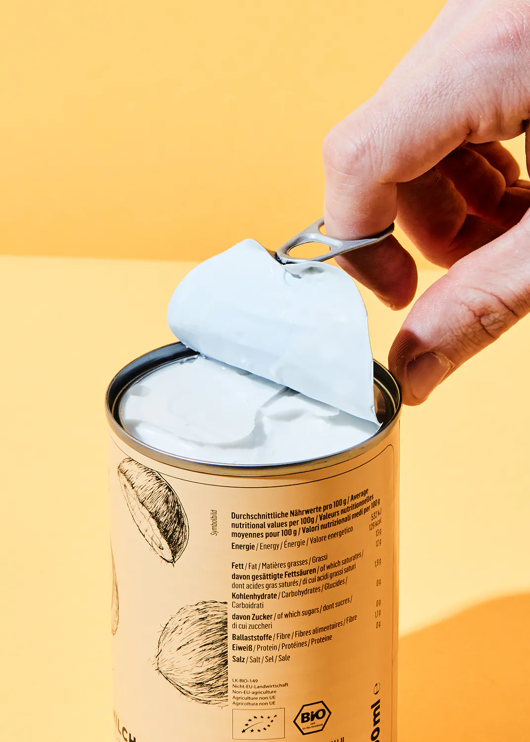 une personne ouvre une boîte de lait de coco bio