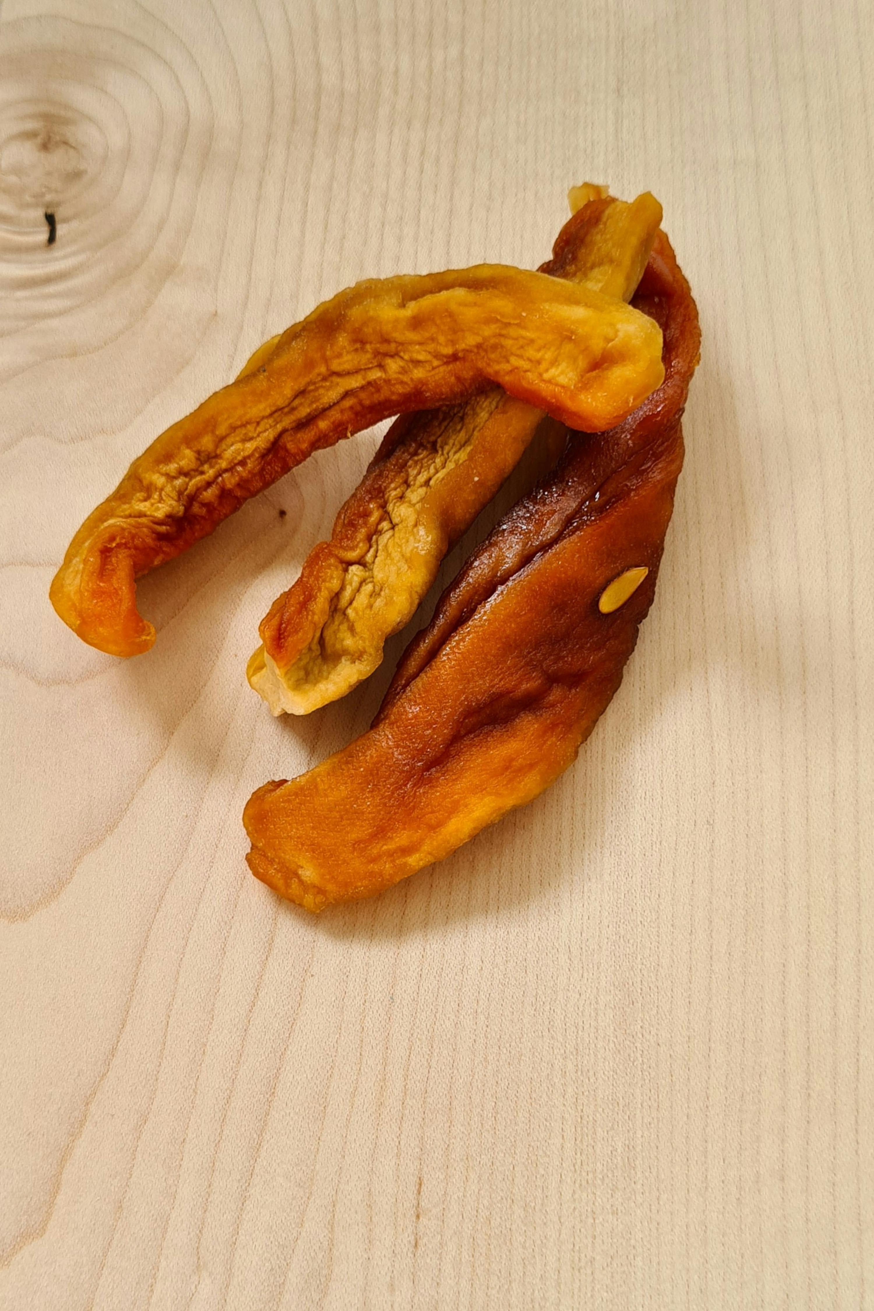 ein Stück getrockneter Banane liegt auf einem Holztisch