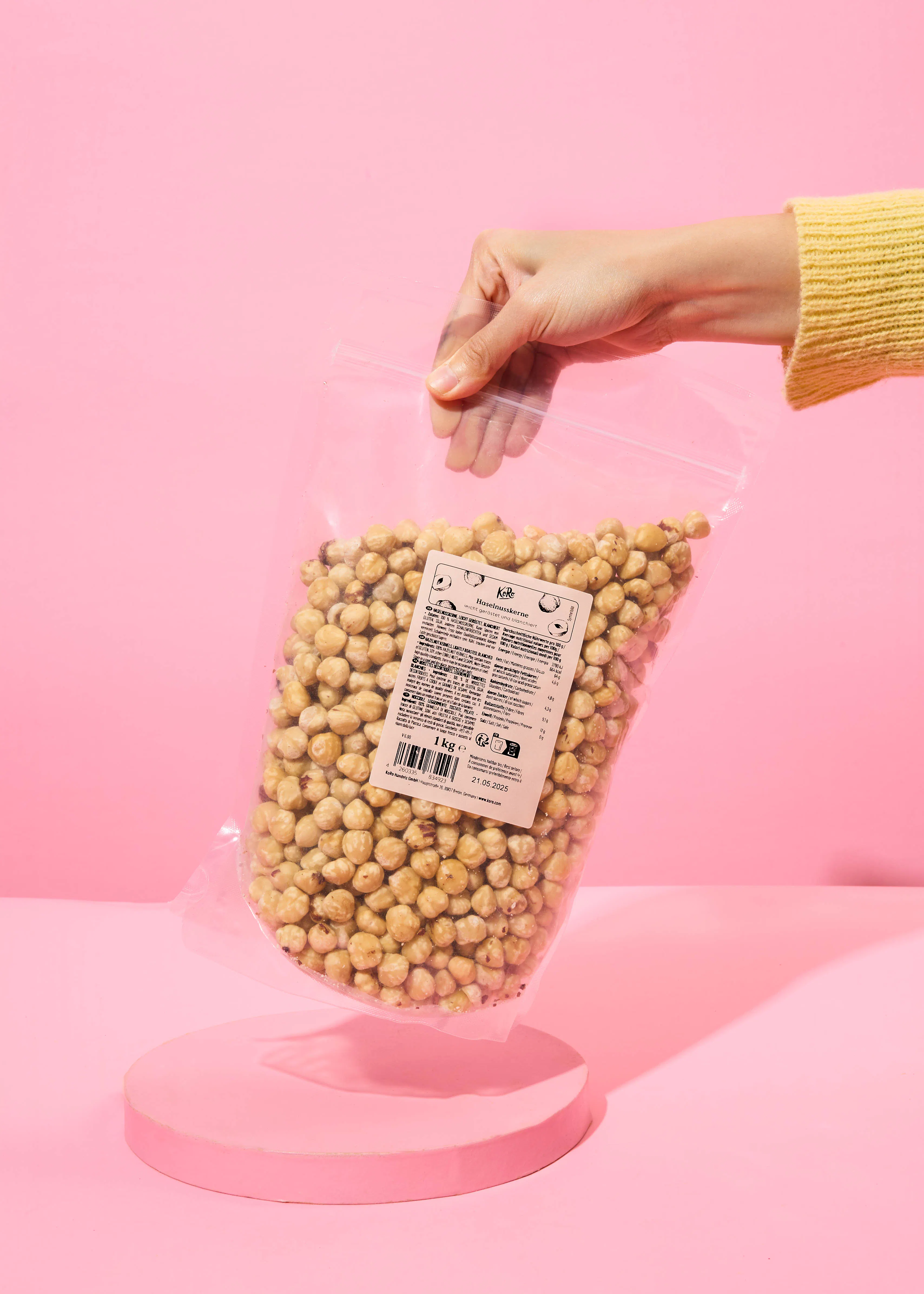 une personne tient un sac de noisettes sur un fond rose