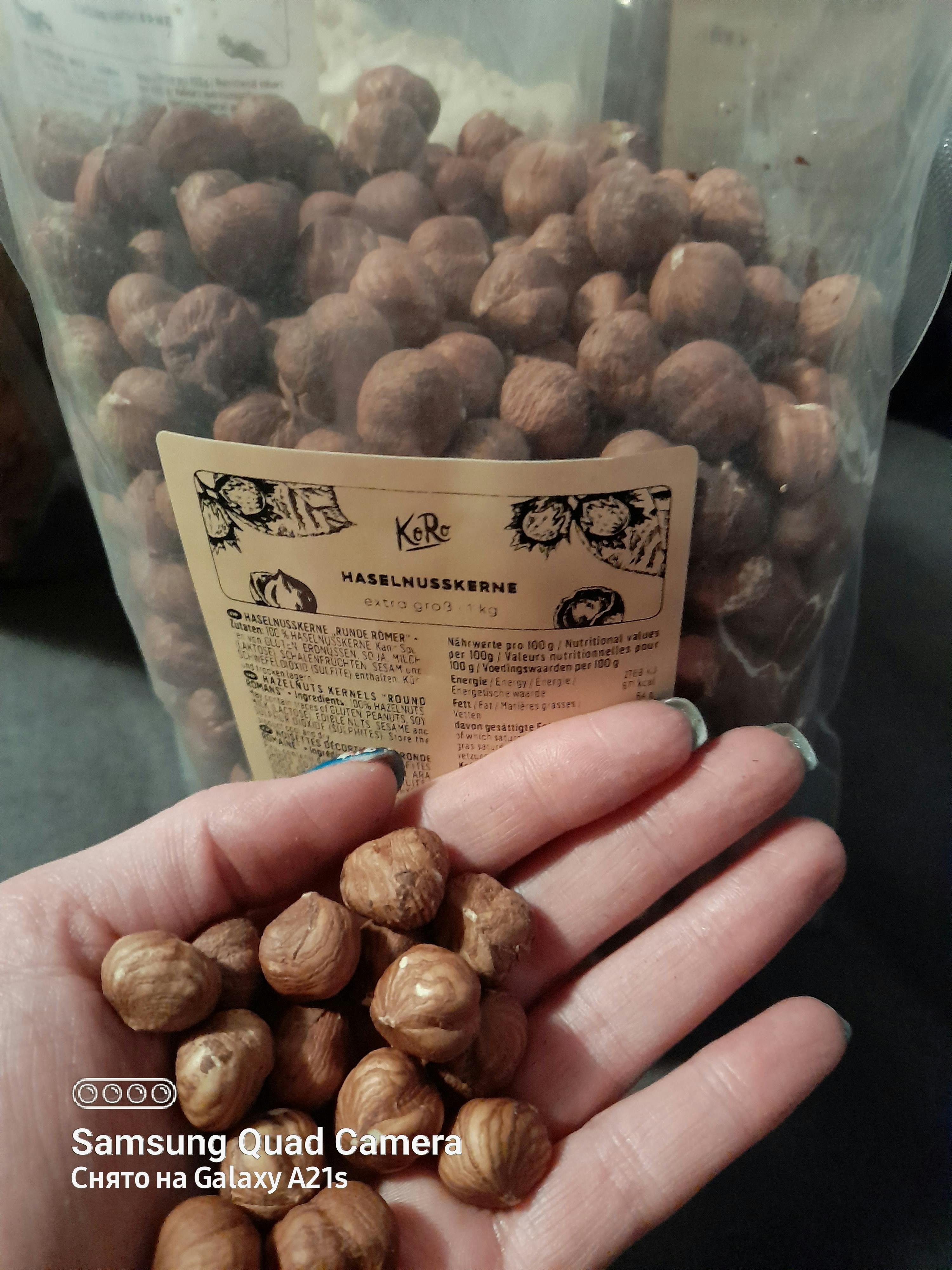 una persona tiene in mano un sacchetto di nocciole e una samsung quad camera