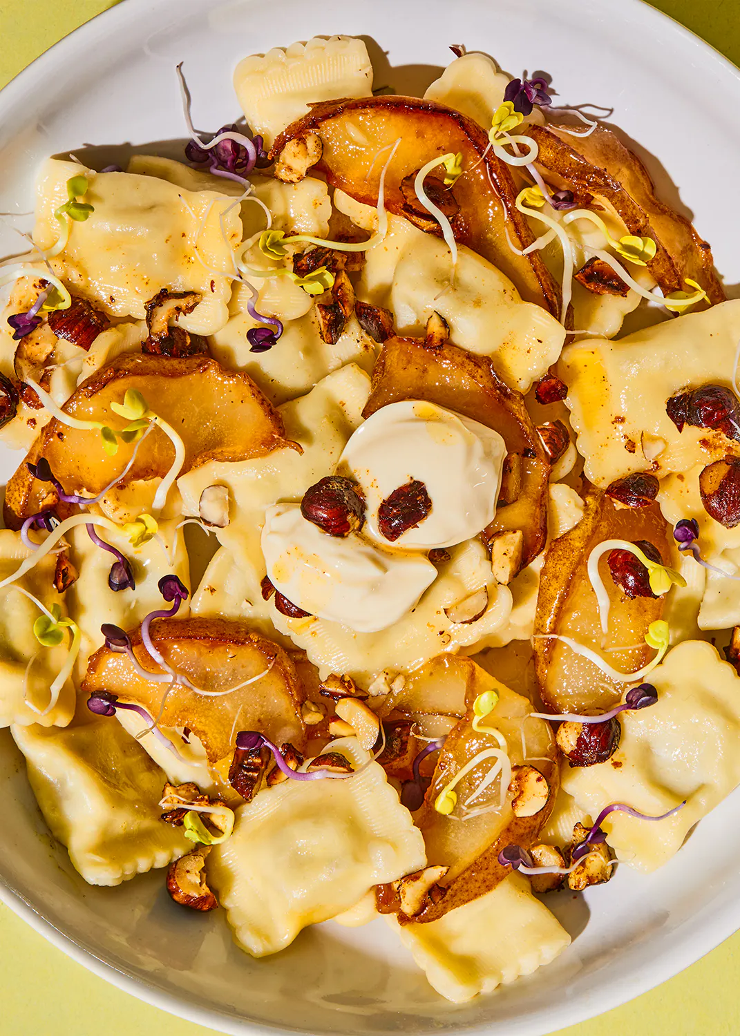 a close up of a plate of pasta with nuts and sprouts