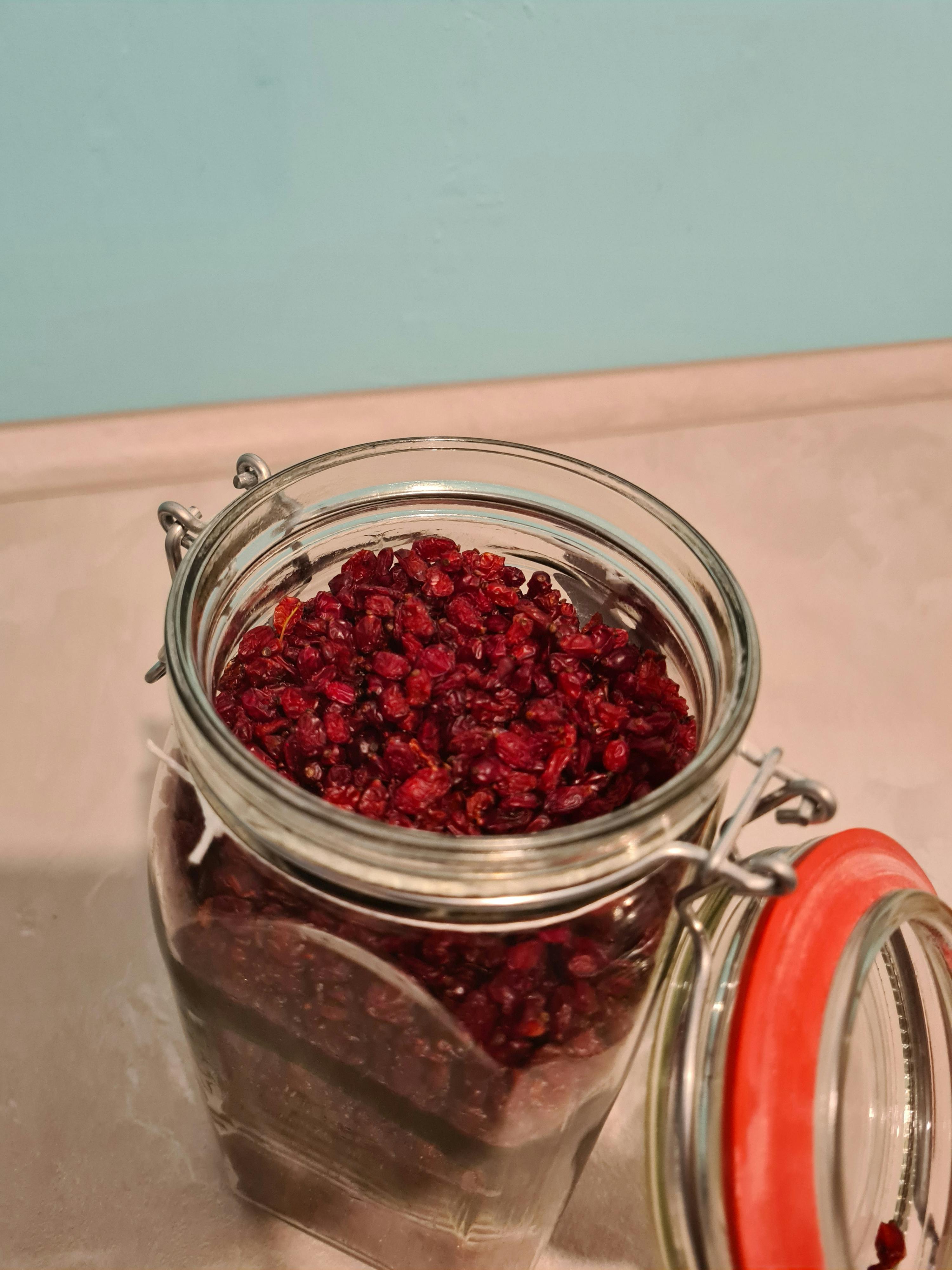 un barattolo di vetro pieno di mirtilli secchi con un coperchio rosso