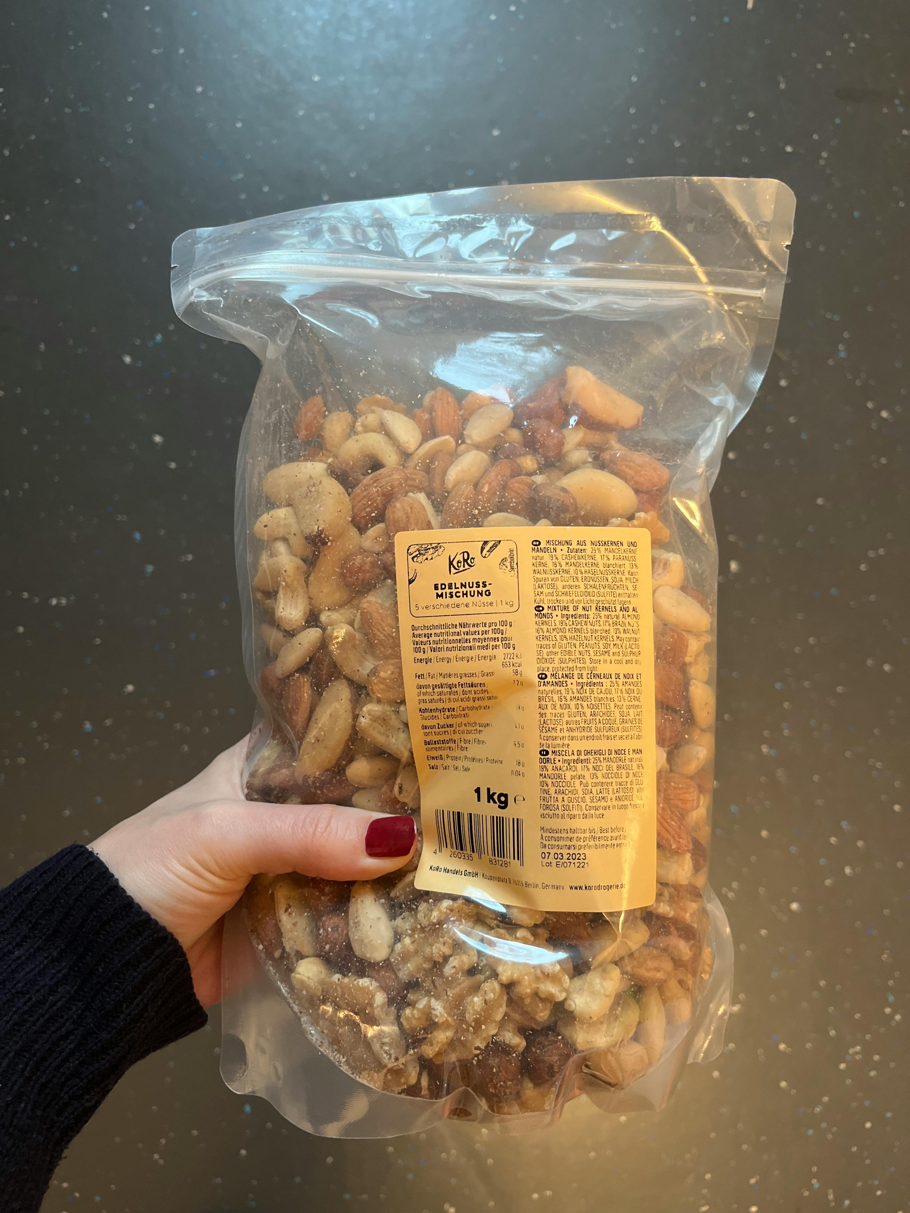 une personne tient un sac de noix mixtes de 1kg