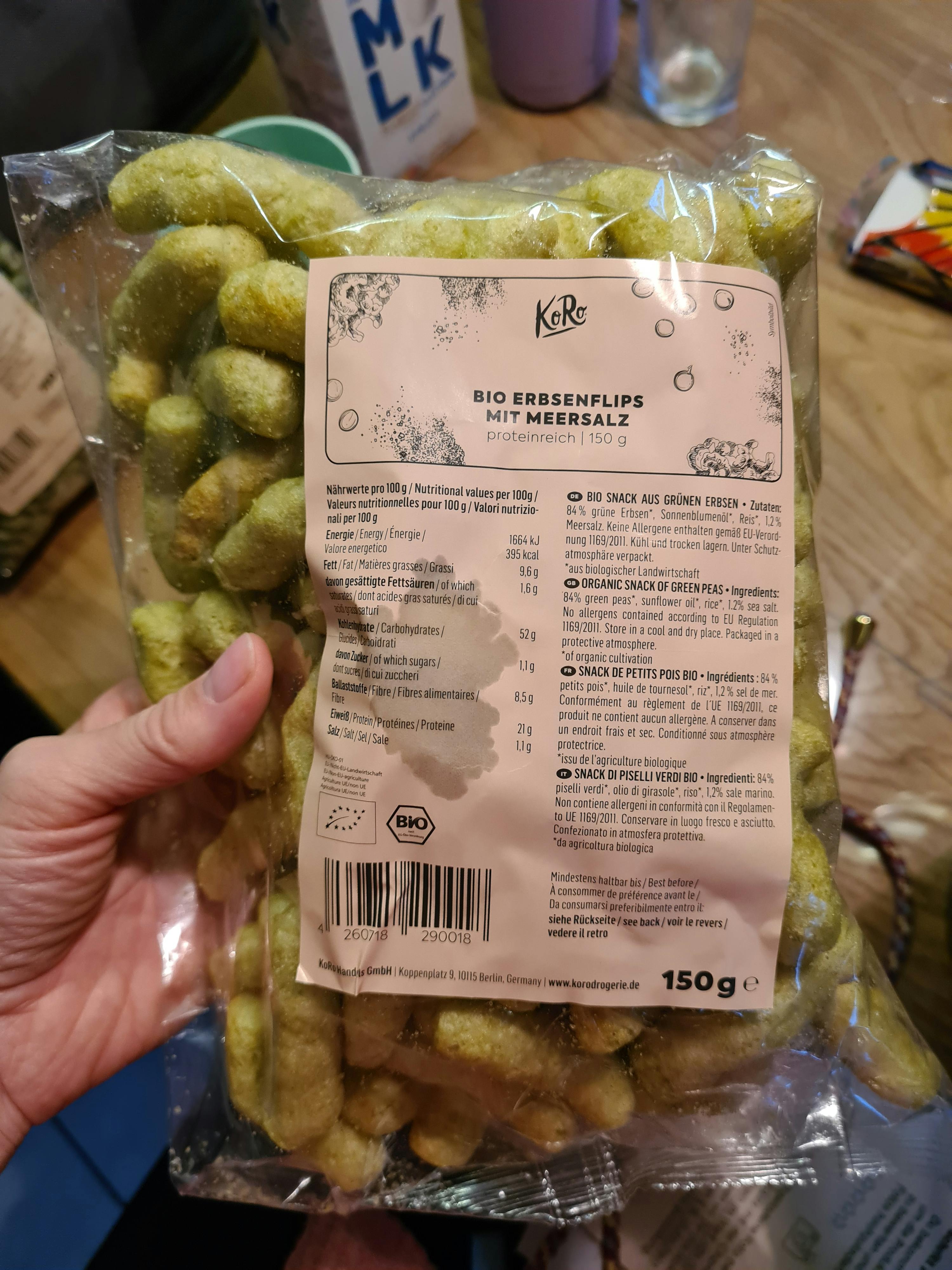 eine Person hält eine Tüte bio Erdnusspuffs mit Meersalz in der Hand