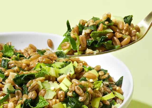 une cuillère remplie d' une salade de graines de blé et de légumes