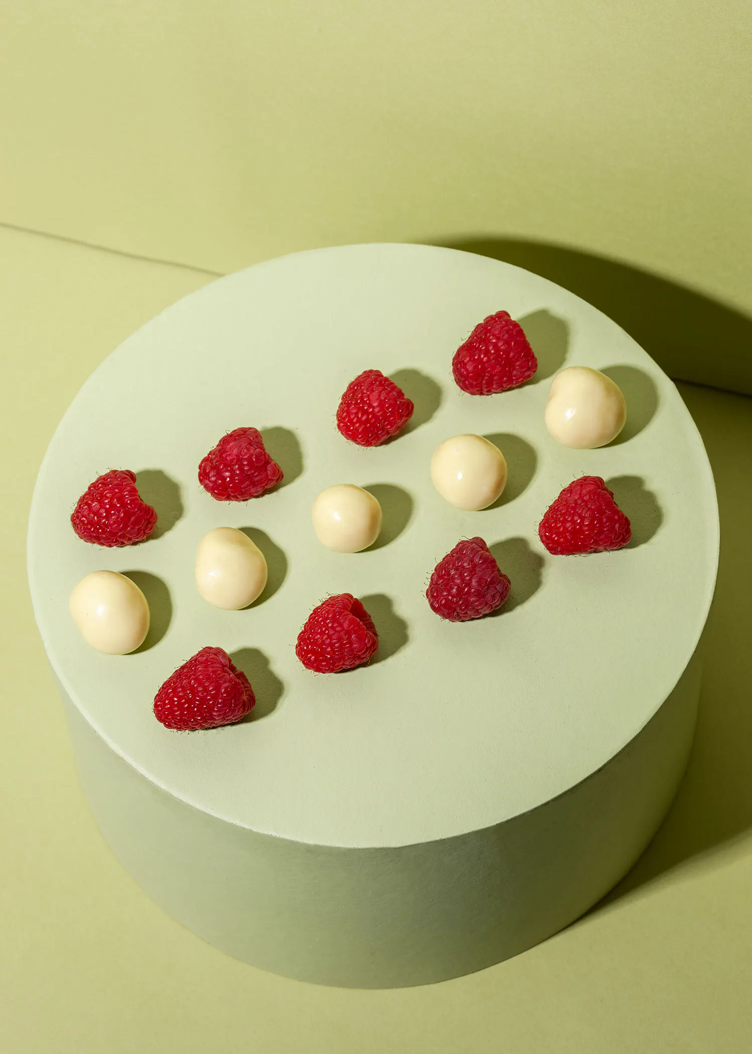 un plateau vert avec des framboises et des bonbons blancs