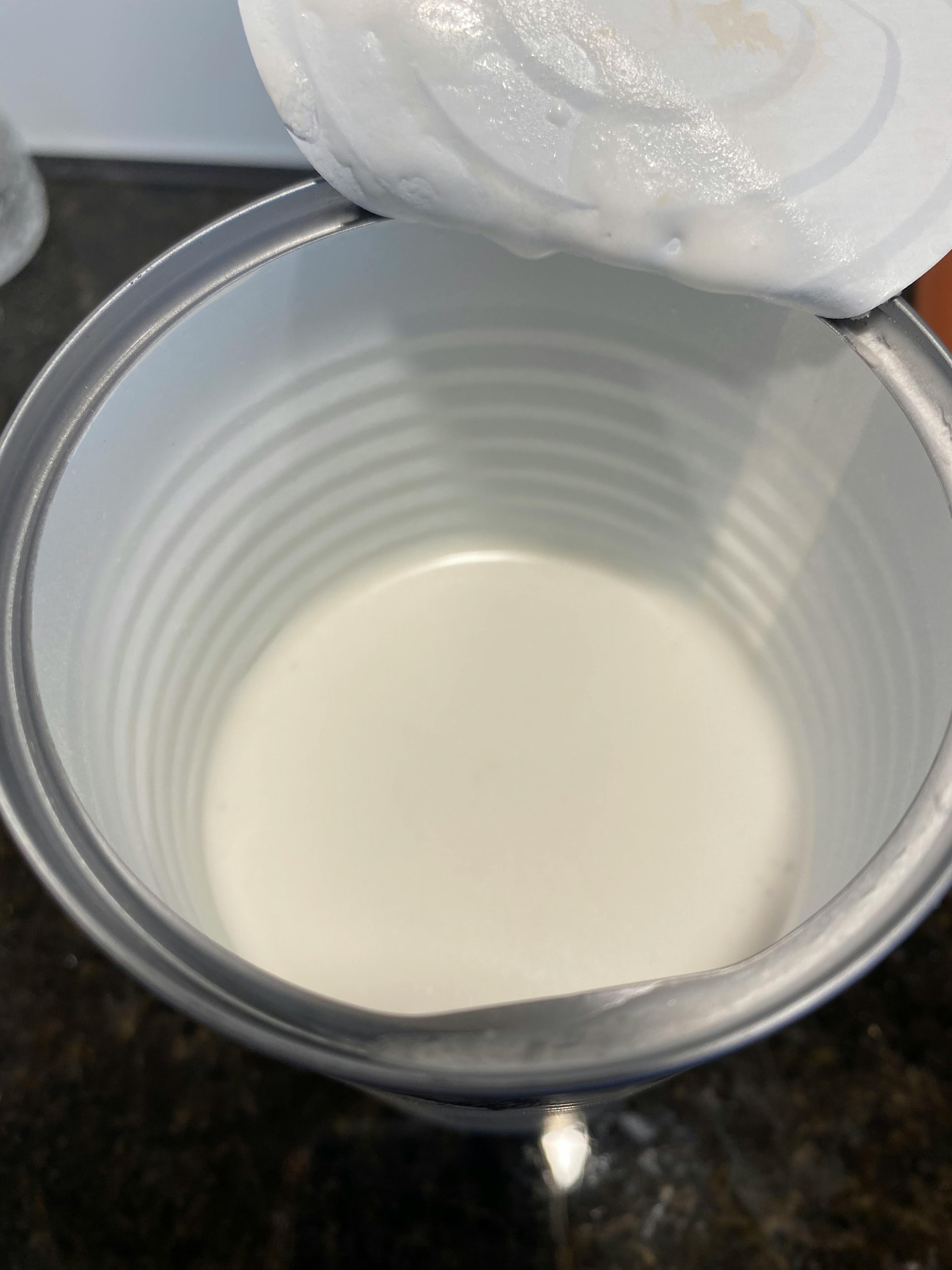a can of milk is being poured into a cup