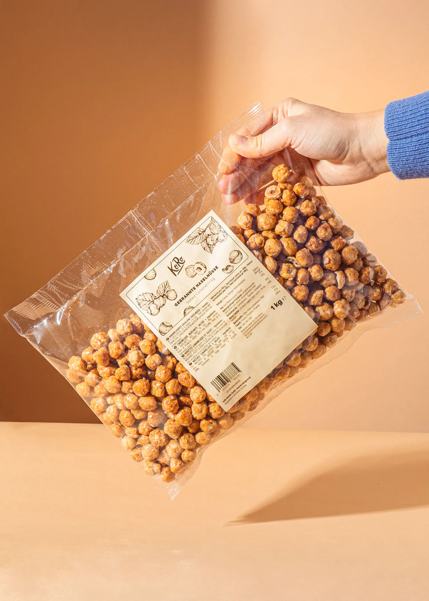 eine Person hält einen Plastikbeutel mit Haselnüssen in der Hand
