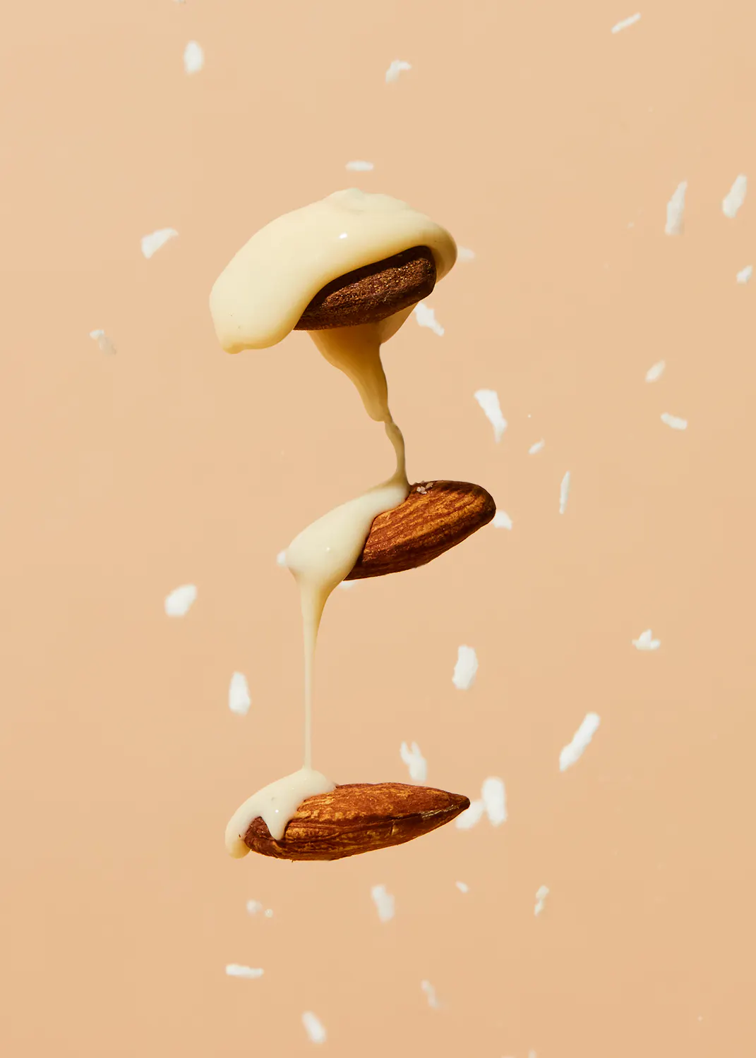 almonds are being drizzled with white liquid on a pink background
