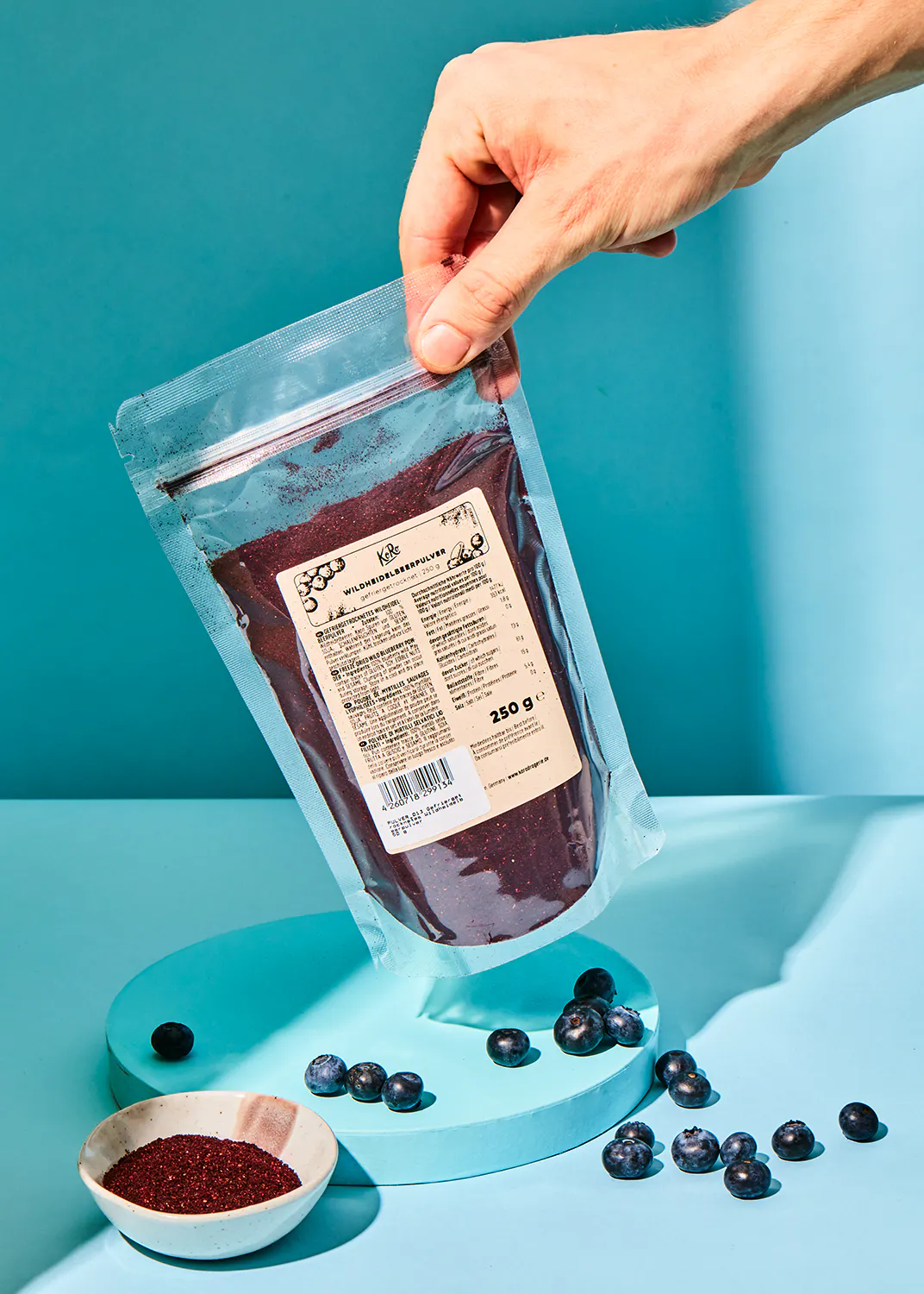 a hand is holding a bag of blueberry powder