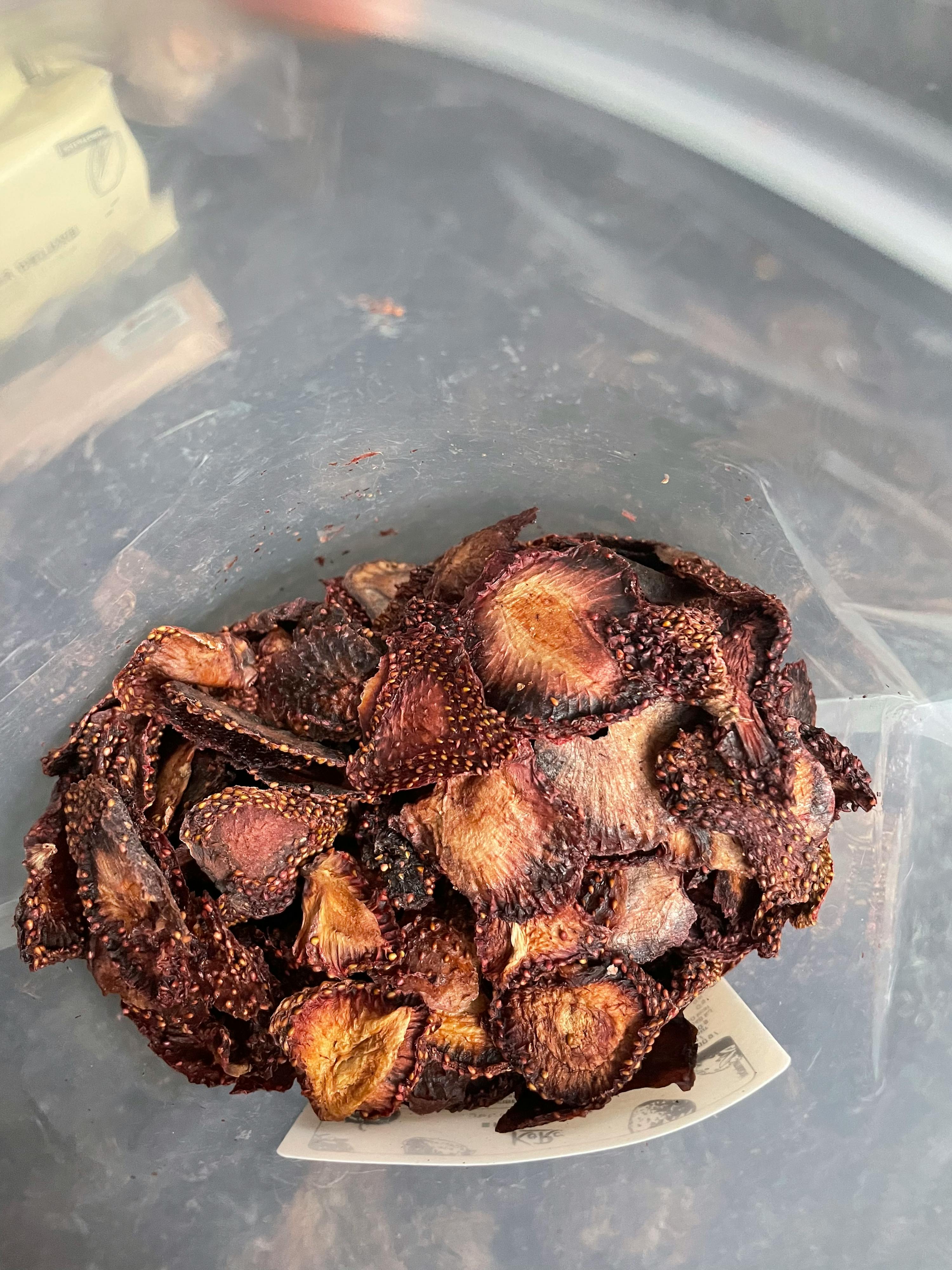 a plastic container filled with a pile of dried strawberries