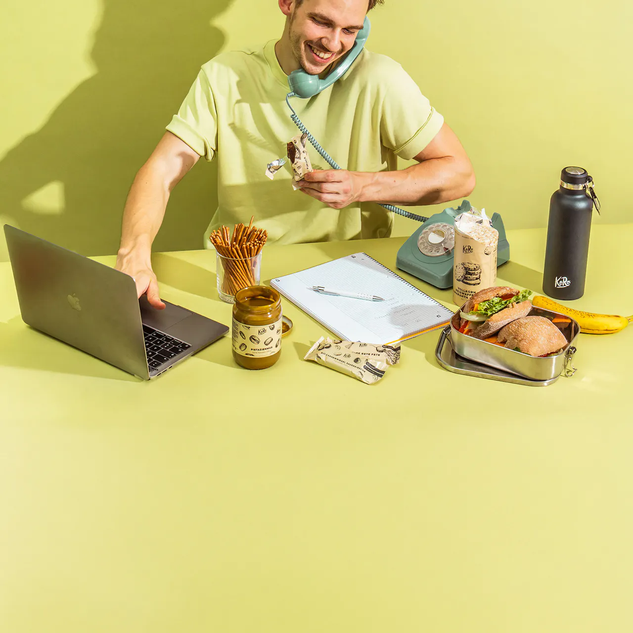 ein Mann sitzt an einem Schreibtisch mit einem Laptop und einer Flasche kaffee