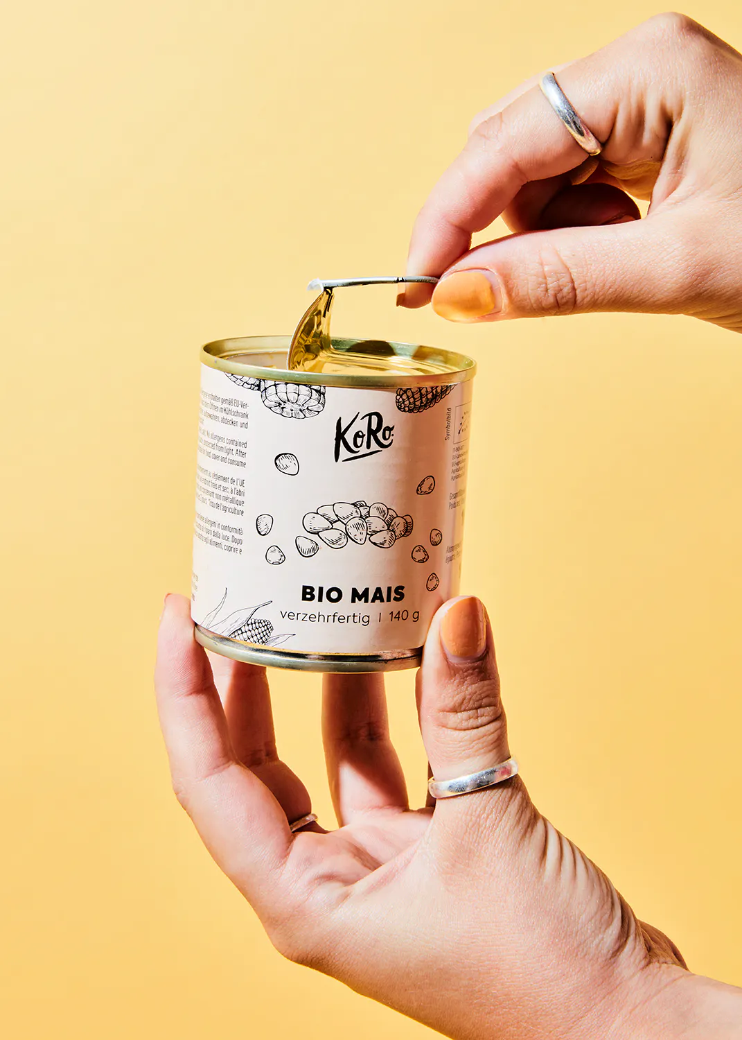 a person is opening a can of koro bio mais
