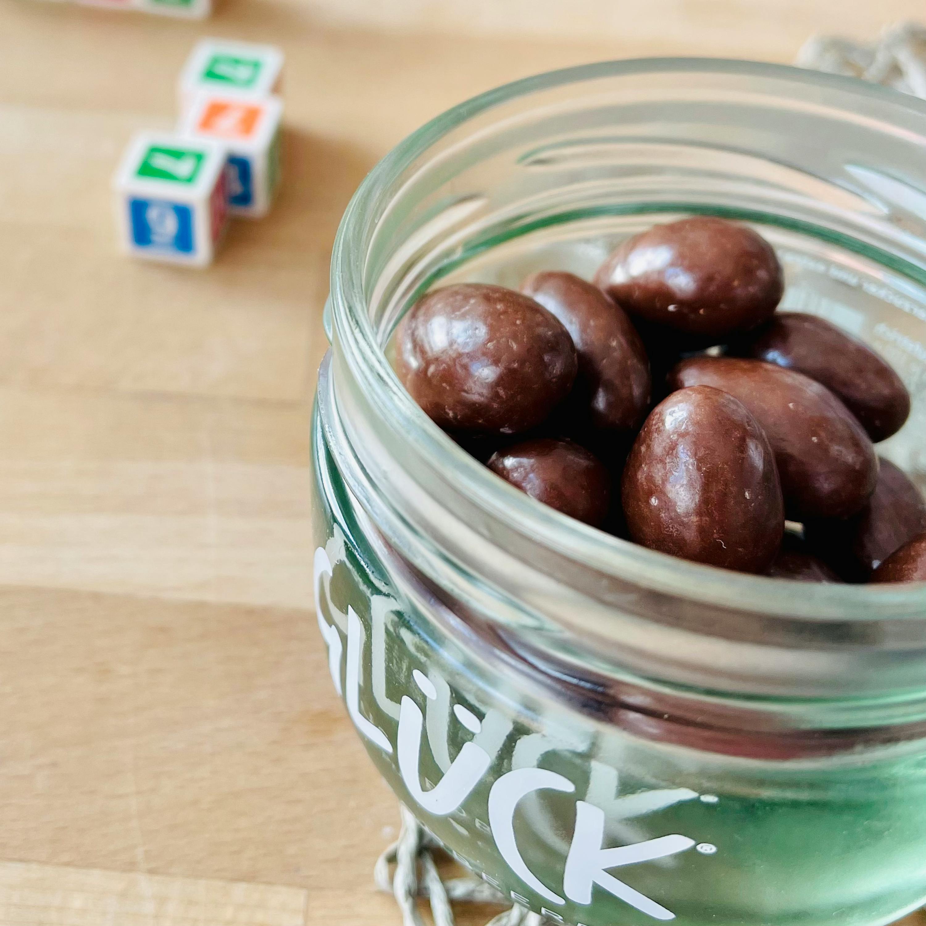 ein Glas mit Schokoladenüberzogenen Erdnüssen steht auf einem Tisch